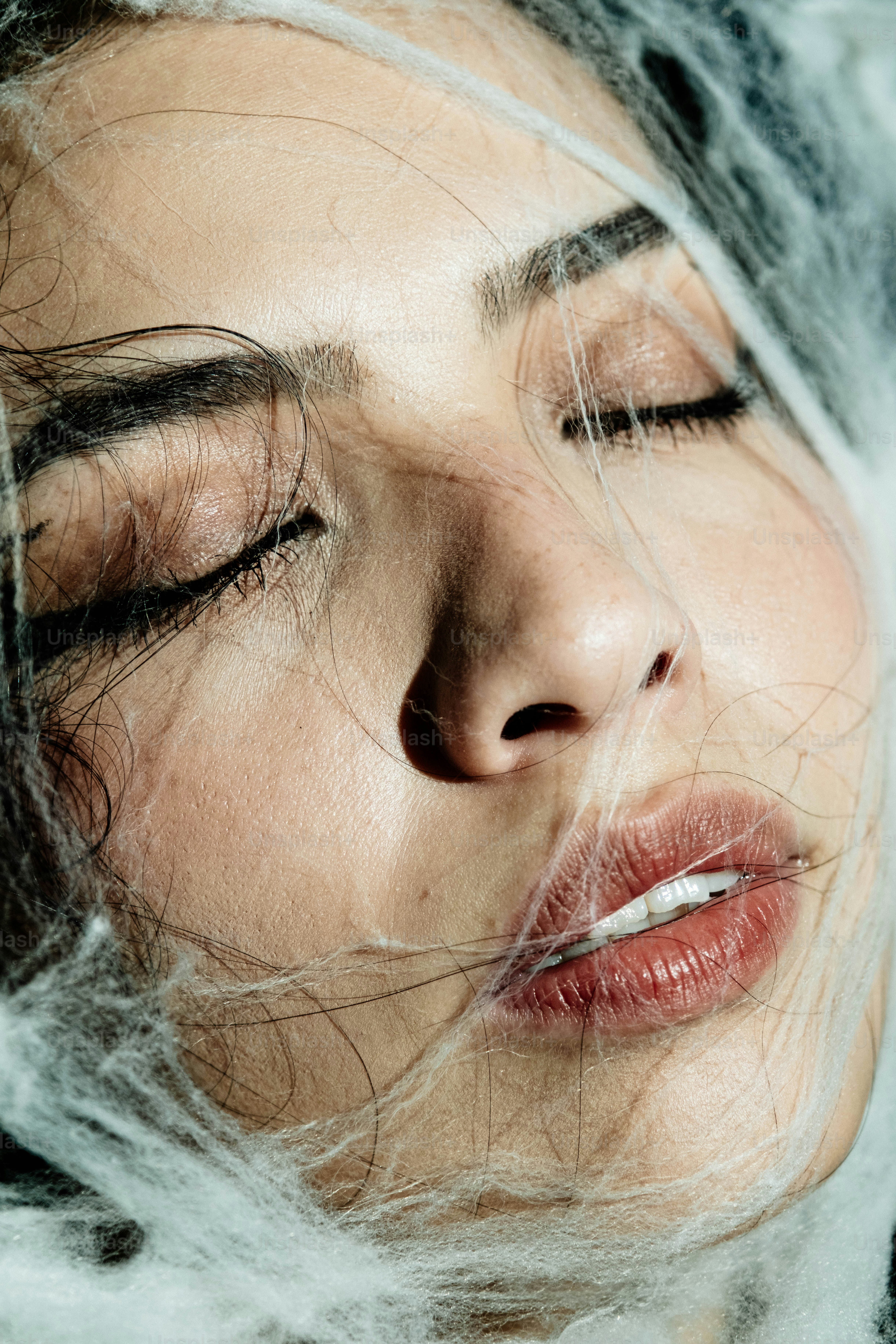 Uma mulher de olhos fechados e fibras brancas e finas no rosto