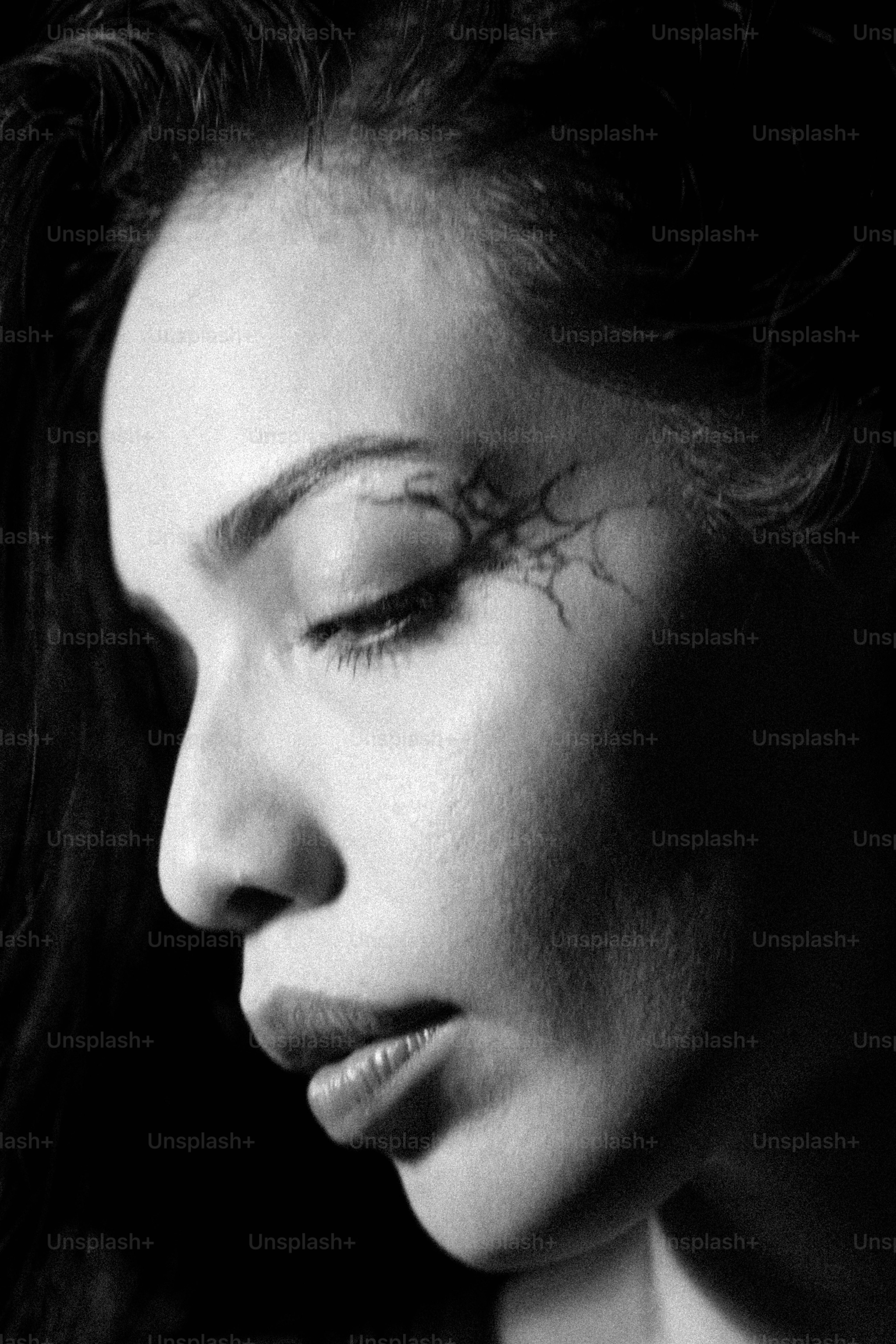 Um perfil em preto e branco de uma mulher com maquiagem escura em forma de teia de aranha