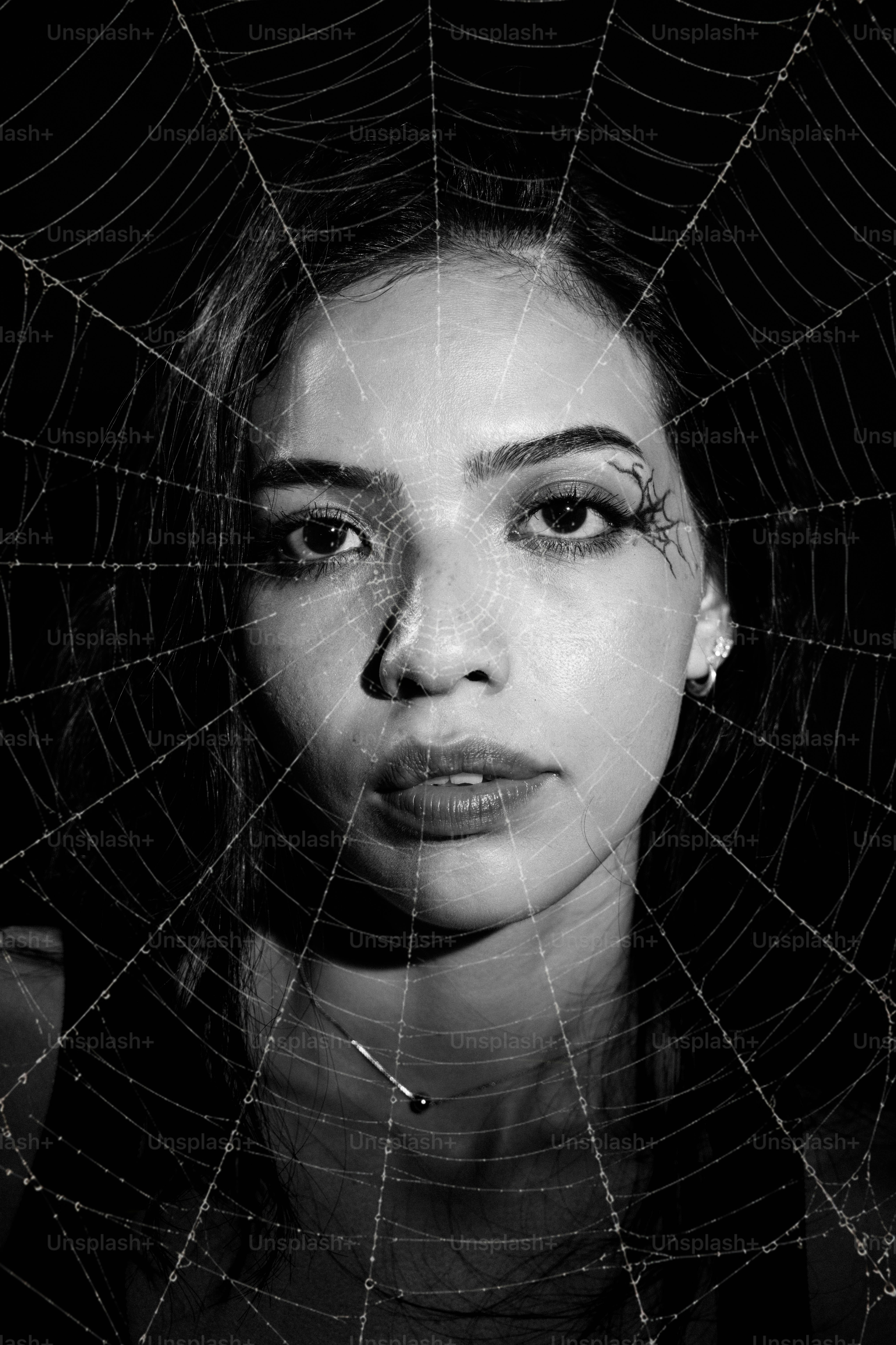 Uma mulher com um padrão de teia de aranha projetado em seu rosto em preto e branco