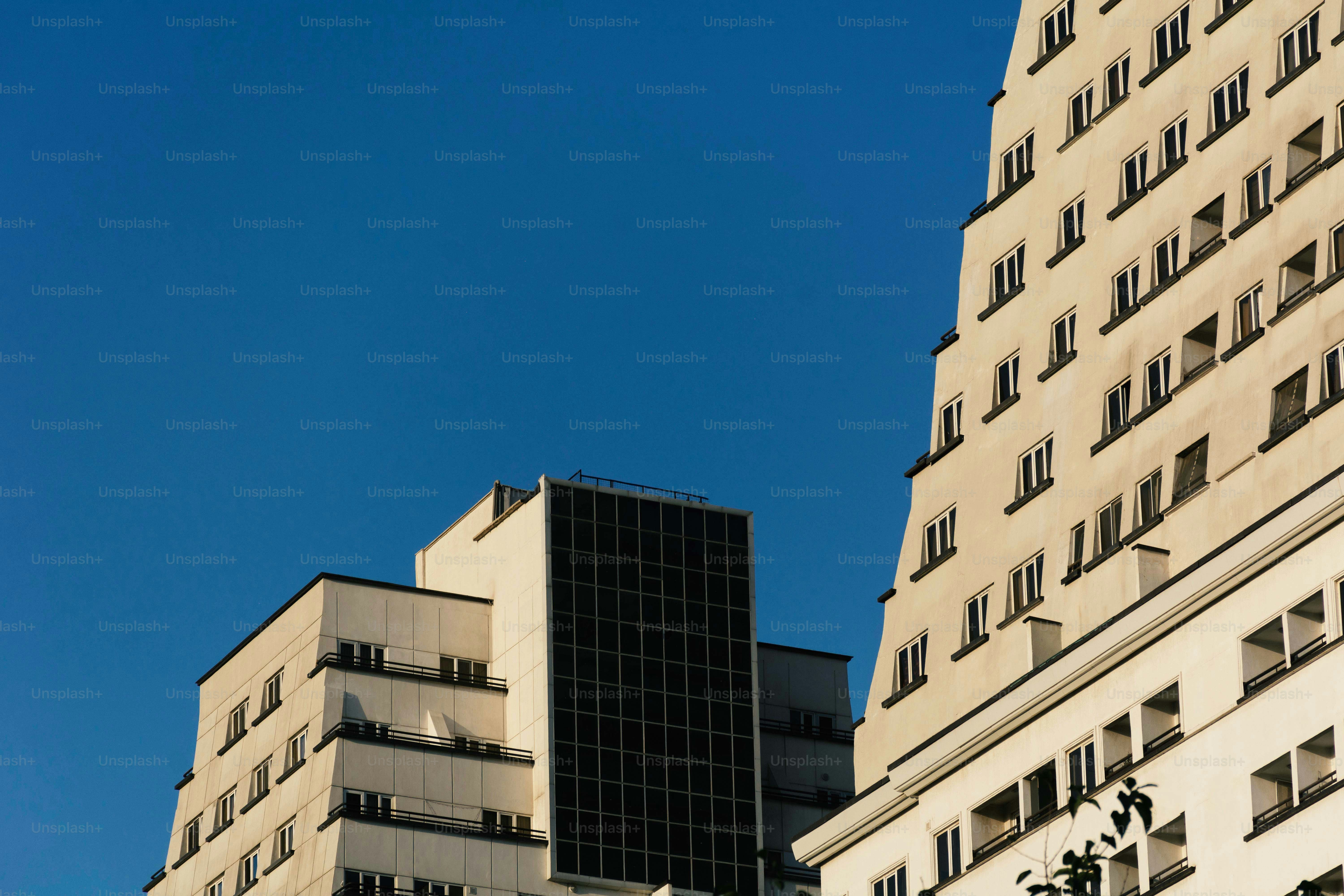 Moderne weiße Wohnhäuser mit dunklen Fenstern vor klarem blauen Himmel