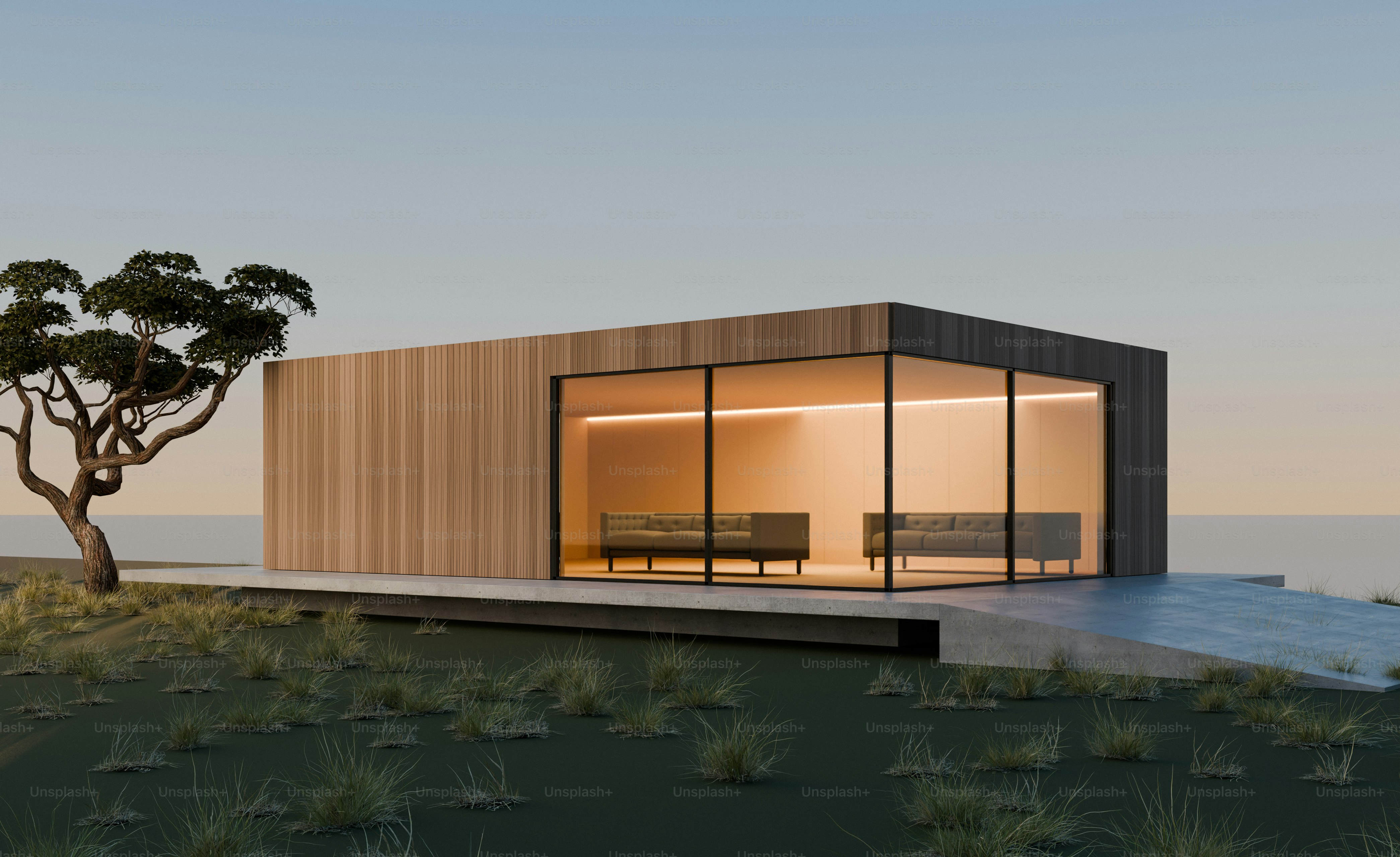 Una cabaña moderna de madera con paredes de cristal y sofás sobre un paisaje cubierto de césped