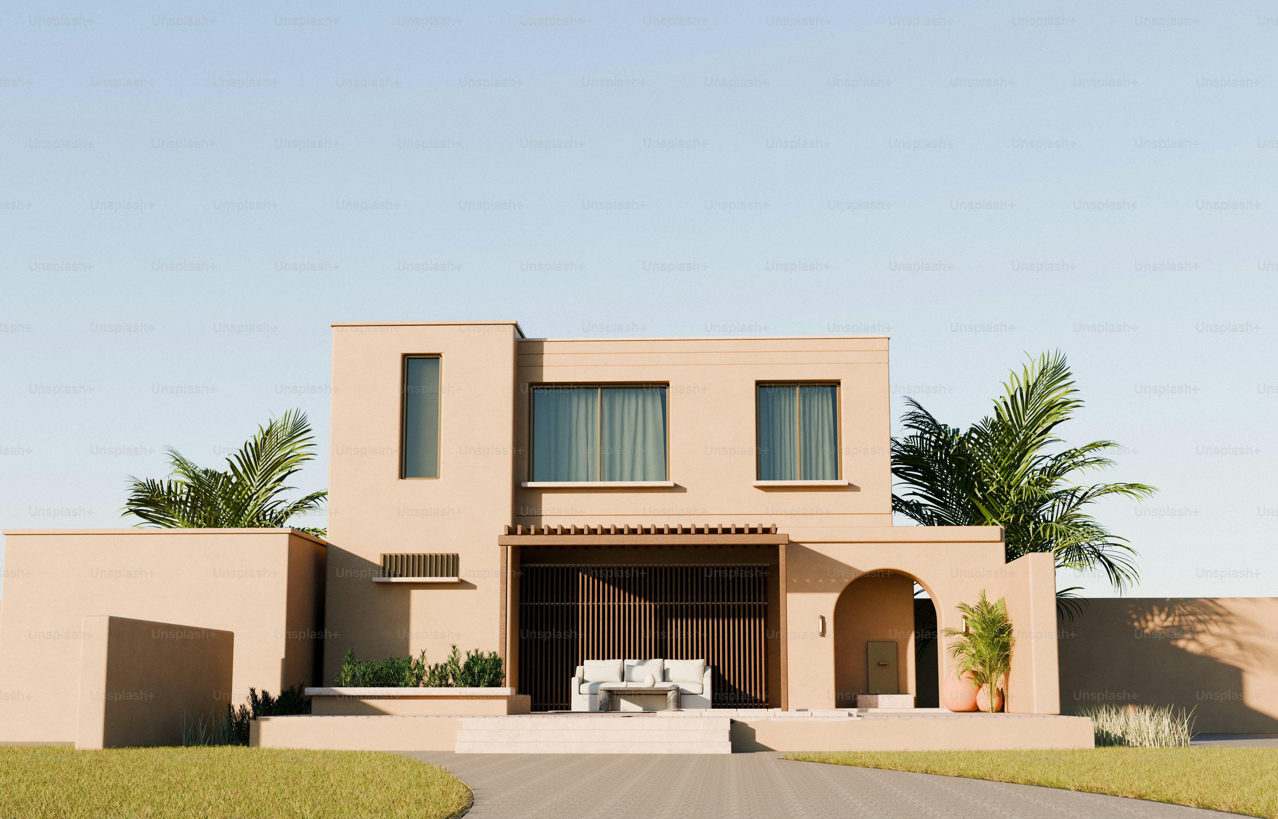 Una casa moderna beige con palmeras y un patio bajo un cielo despejado