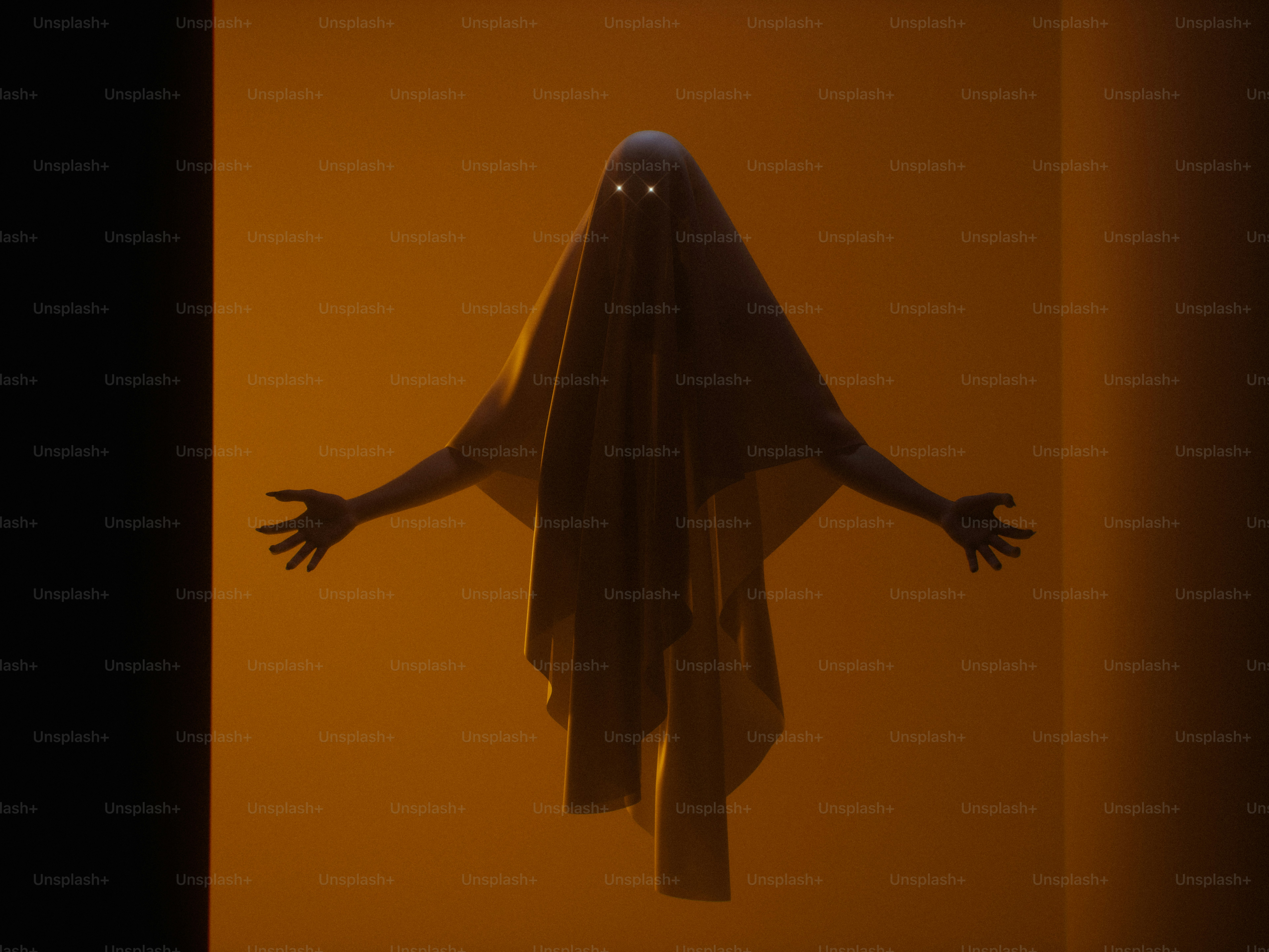 A person draped in a white sheet with glowing eyes against an orange background