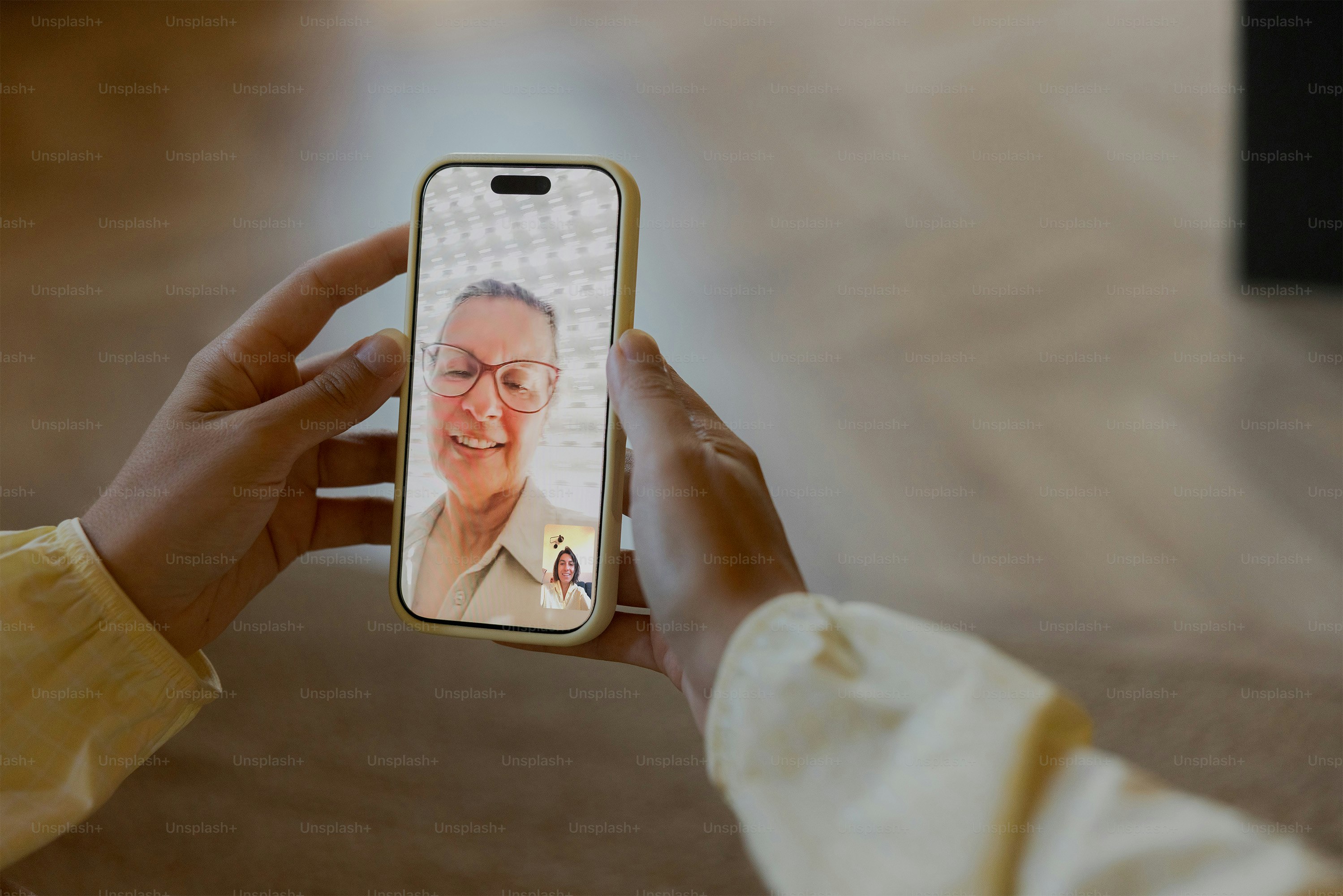 A person holding a smartphone displaying a video call with an older woman