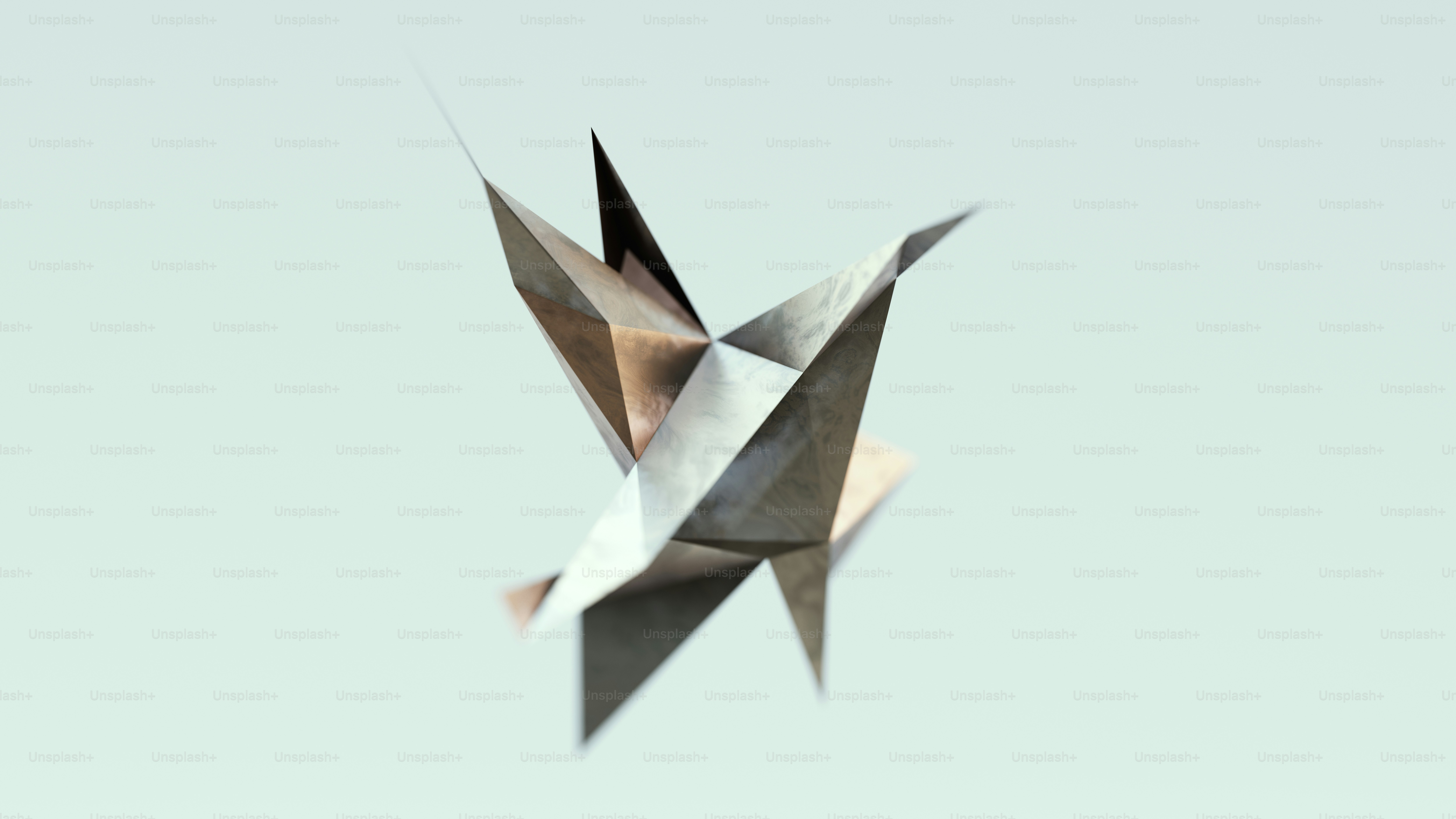 A metallic geometric sculpture with sharp edges against a pale blue background