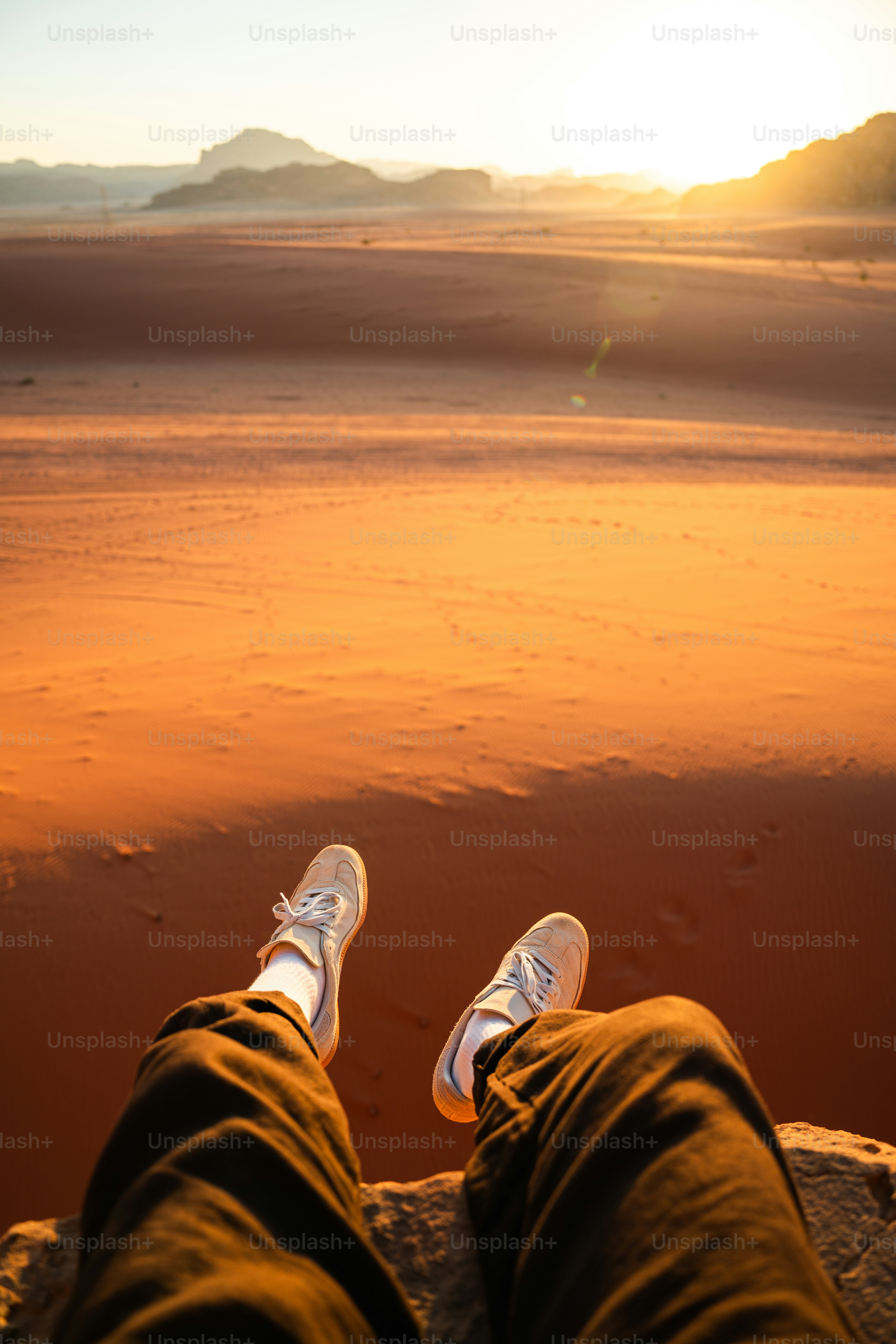 A person wearing sneakers and dark trousers overlooking the desert in Wadi Rum, Jordan
