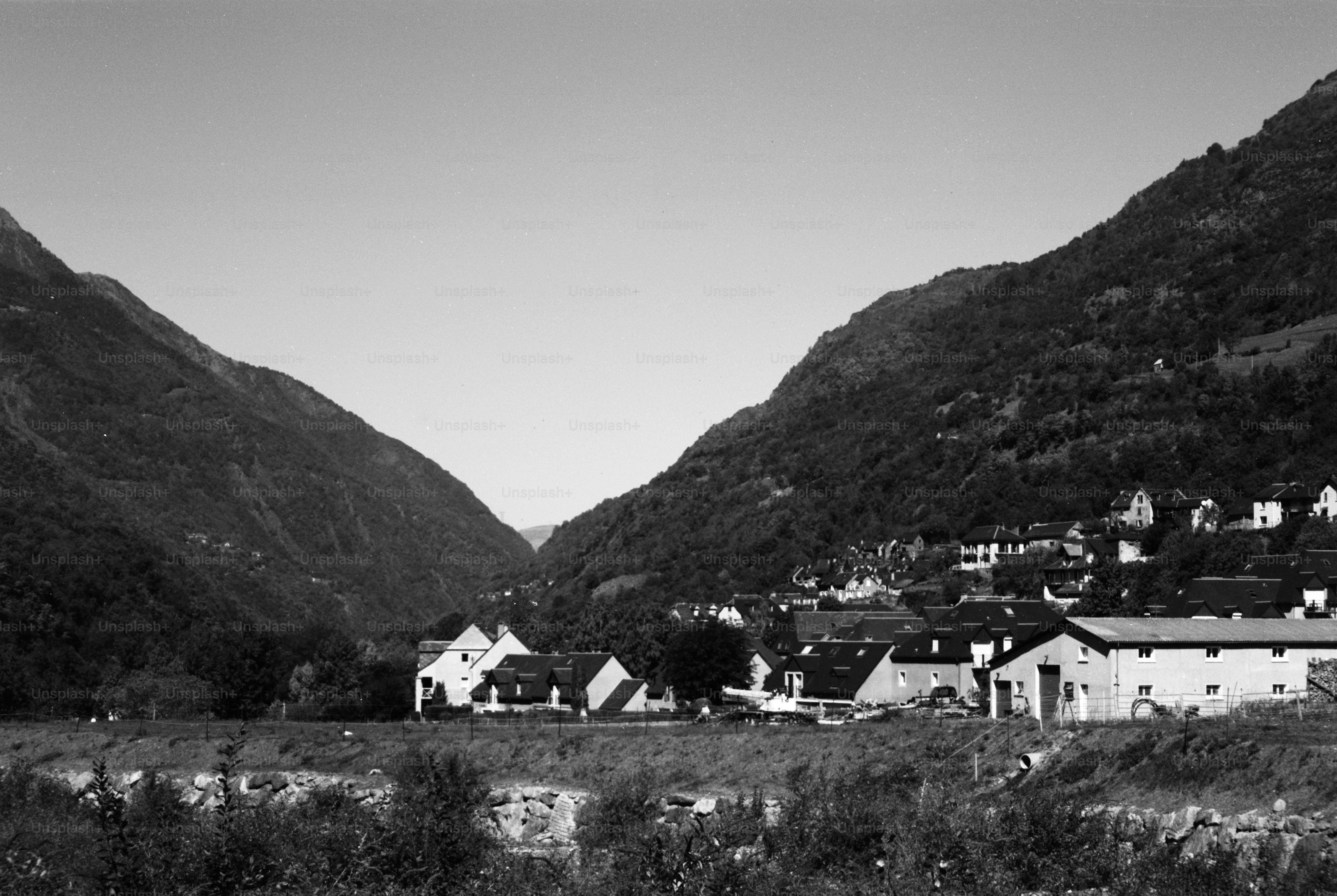 A black and white view of a village nestled between two steep mountains