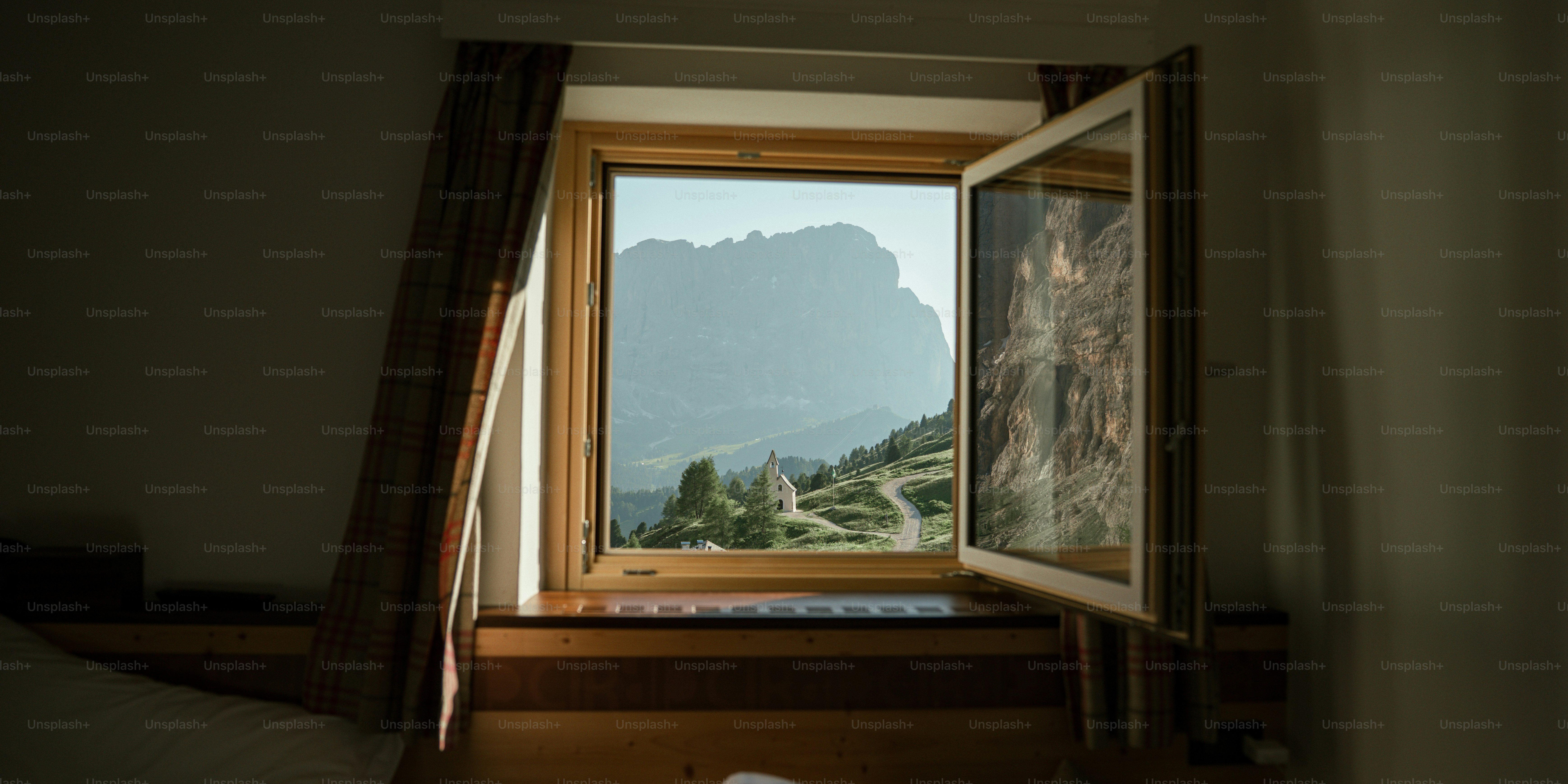 A view of a mountain chapel and winding road through an open window