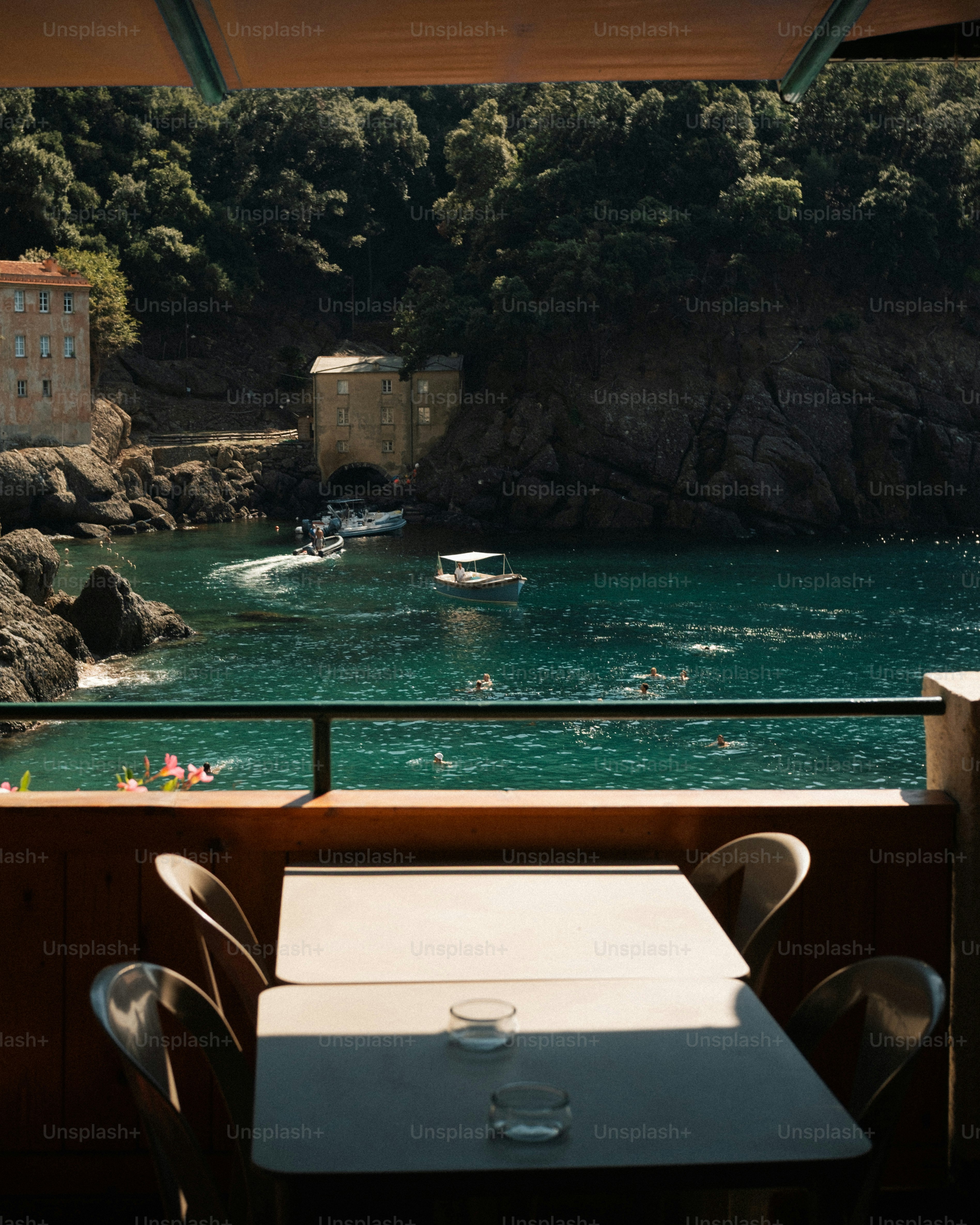 A view of the San Fruttuoso bay with boats and swimmers from a balcony
