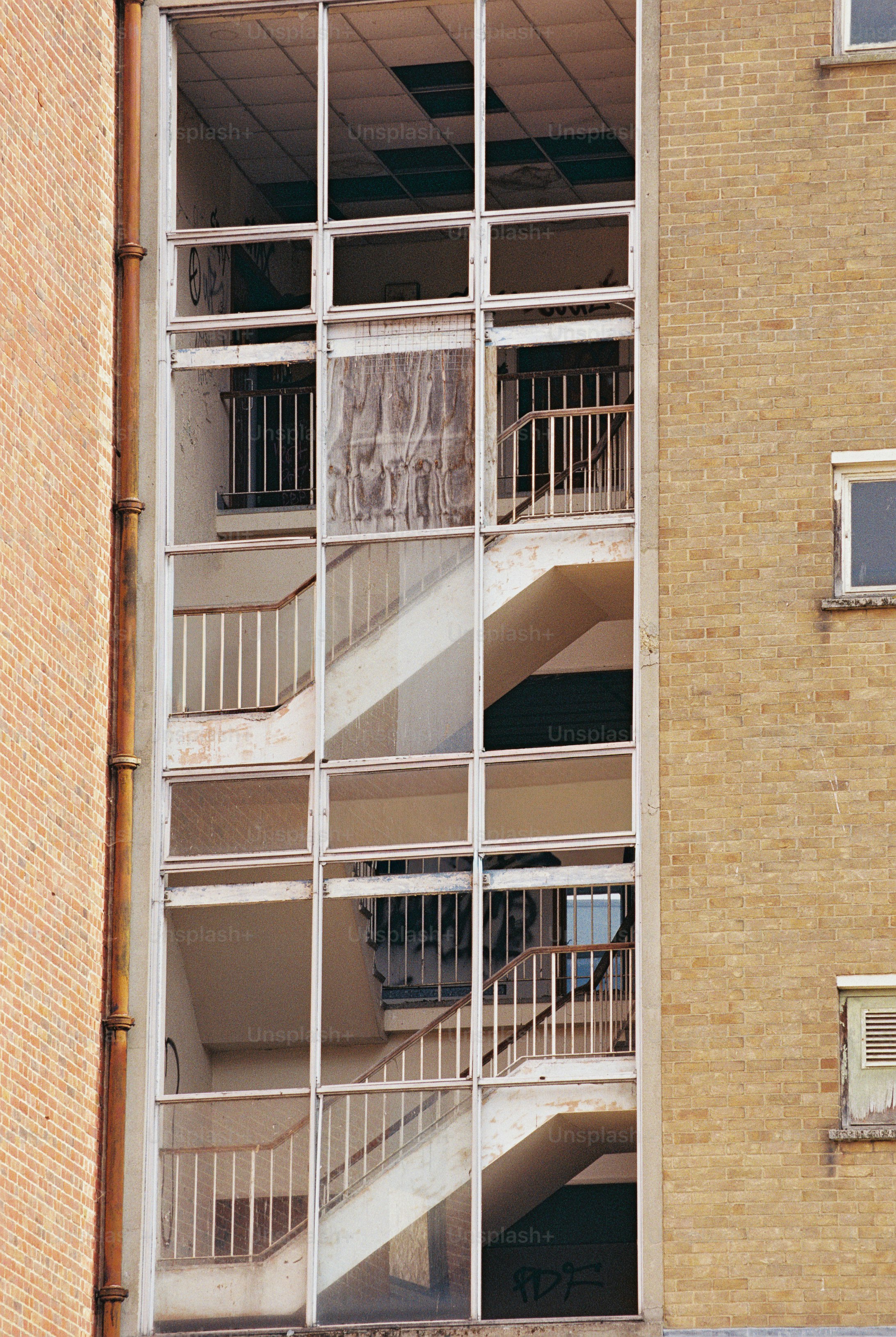 Staircases and metal railings visible through a glazed stairwell on a brick building