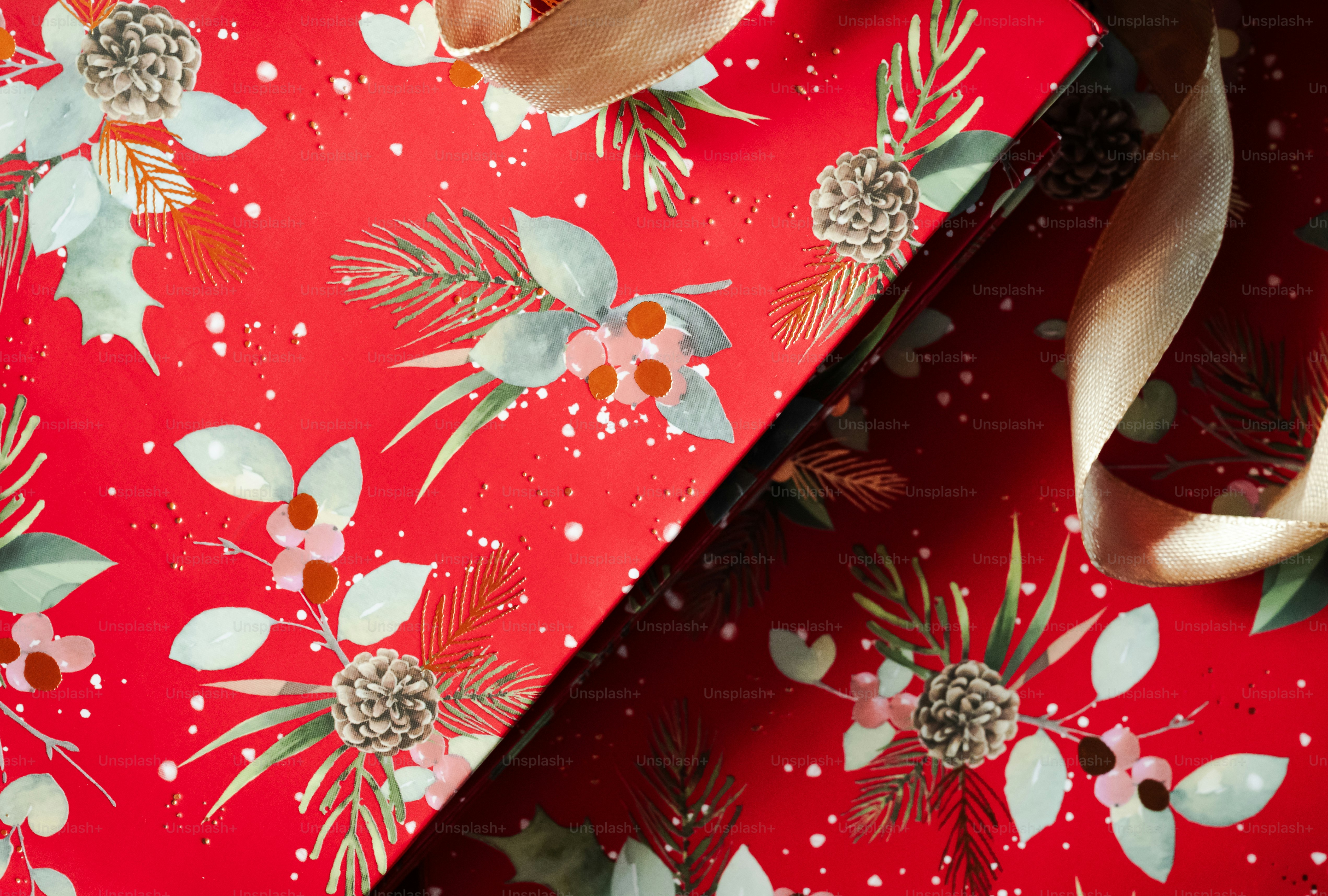 Red wrapping paper with a pattern of pine cones and holly leaves
