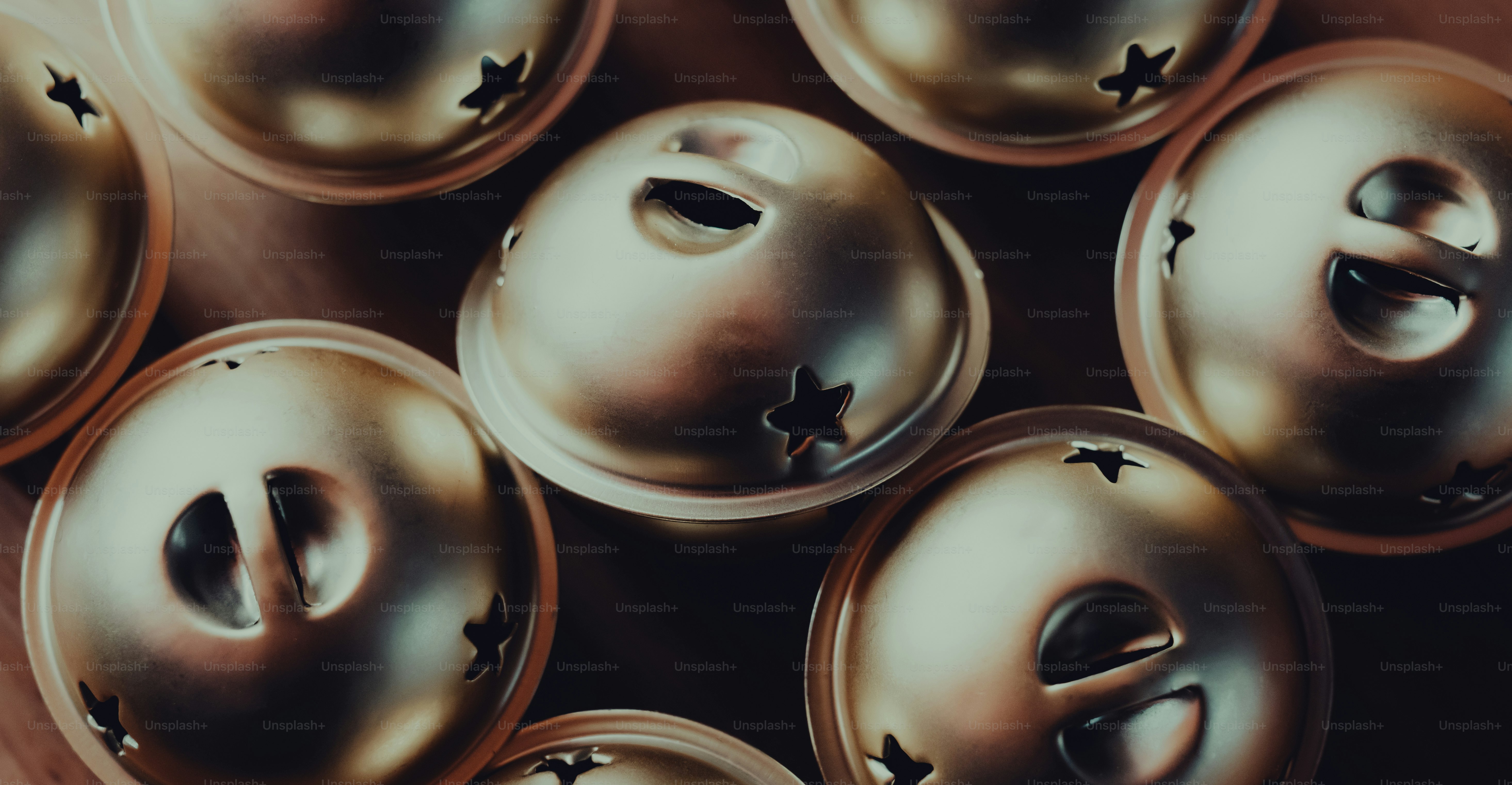 A group of gold jingle bells with star-shaped cutouts on a dark surface