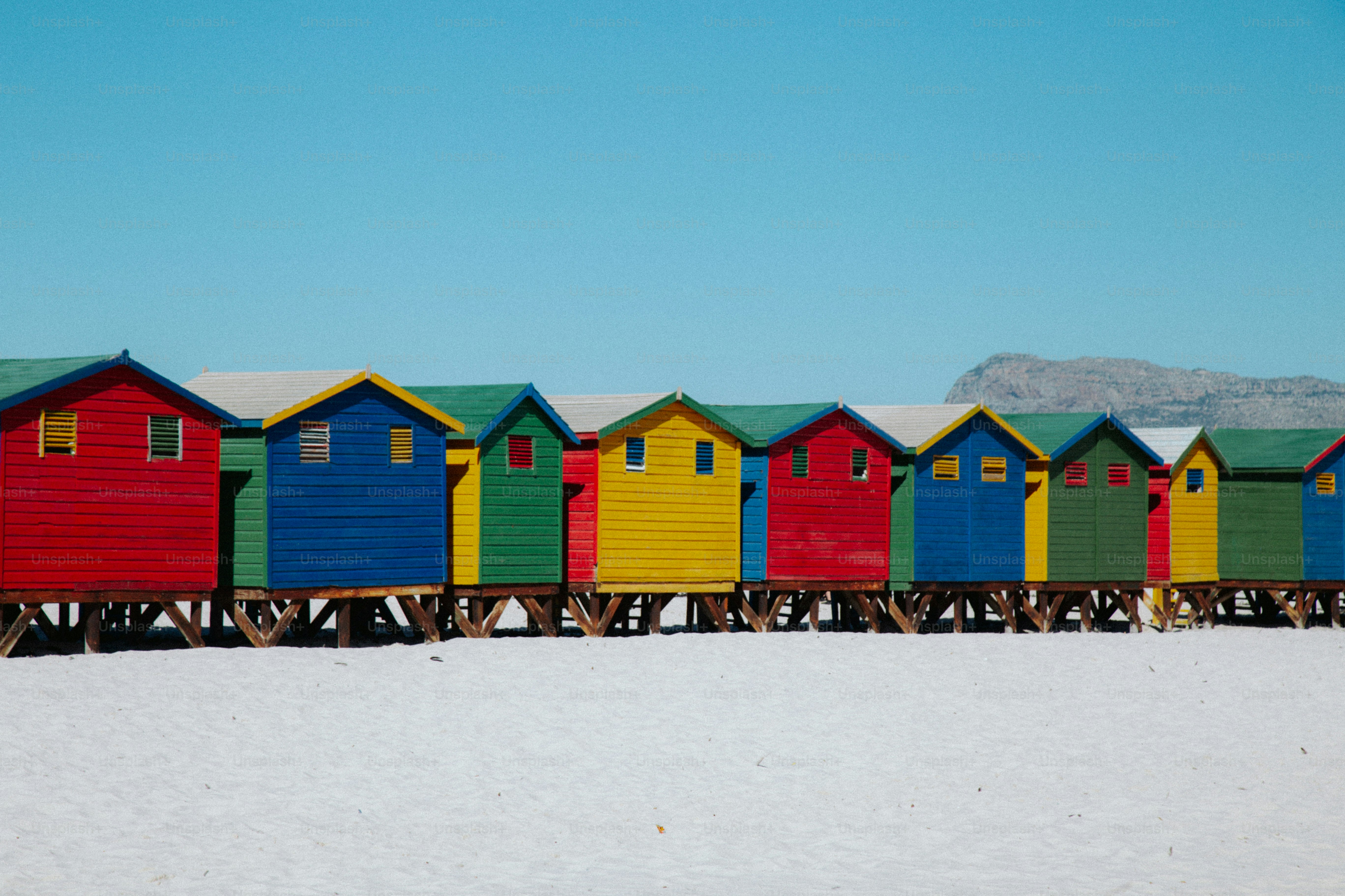 Una fila de coloridas chozas de madera en la playa sobre arena blanca en Ciudad del Cabo