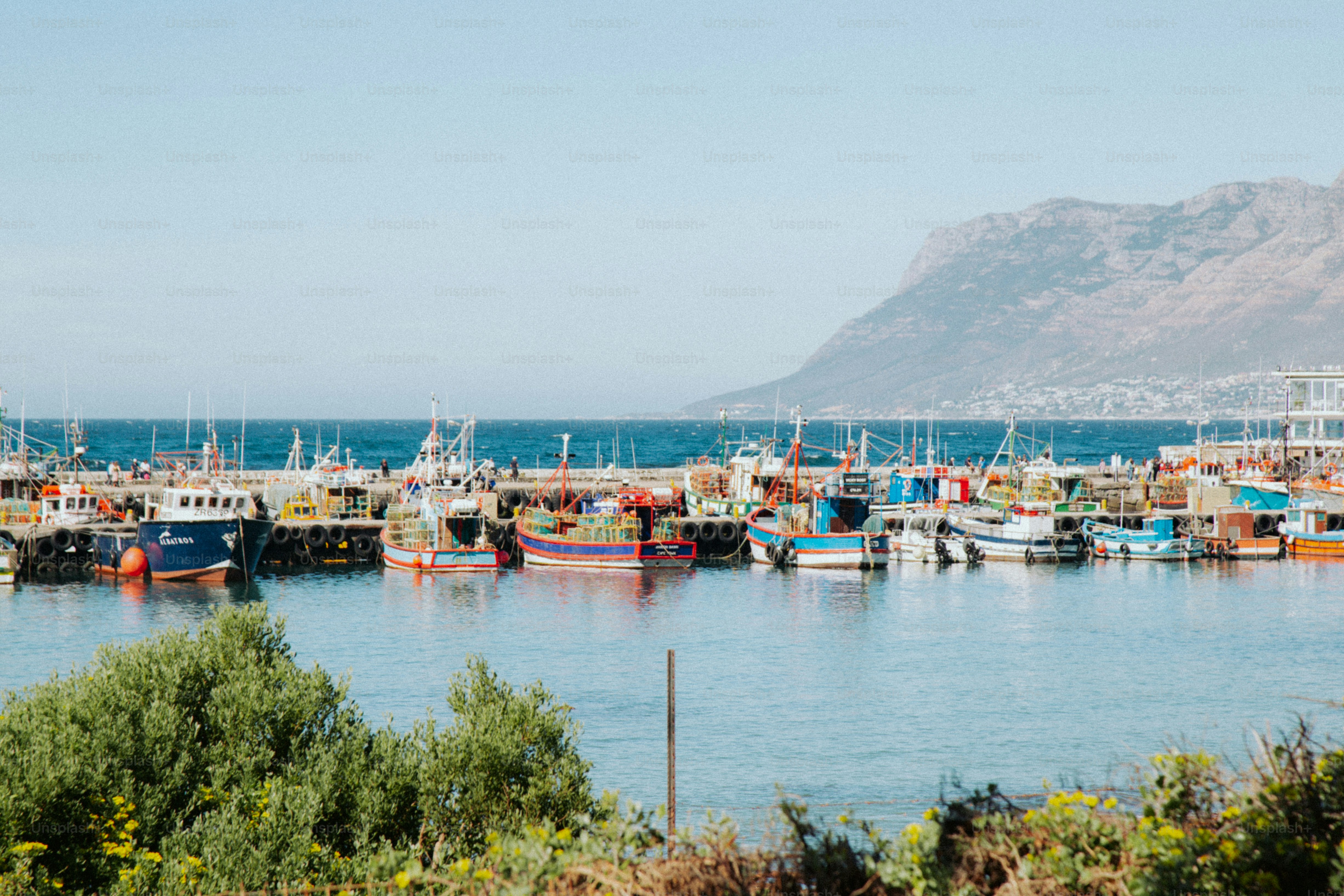Coloridos barcos de pesca atracados en un puerto de Ciudad del Cabo con montañas detrás