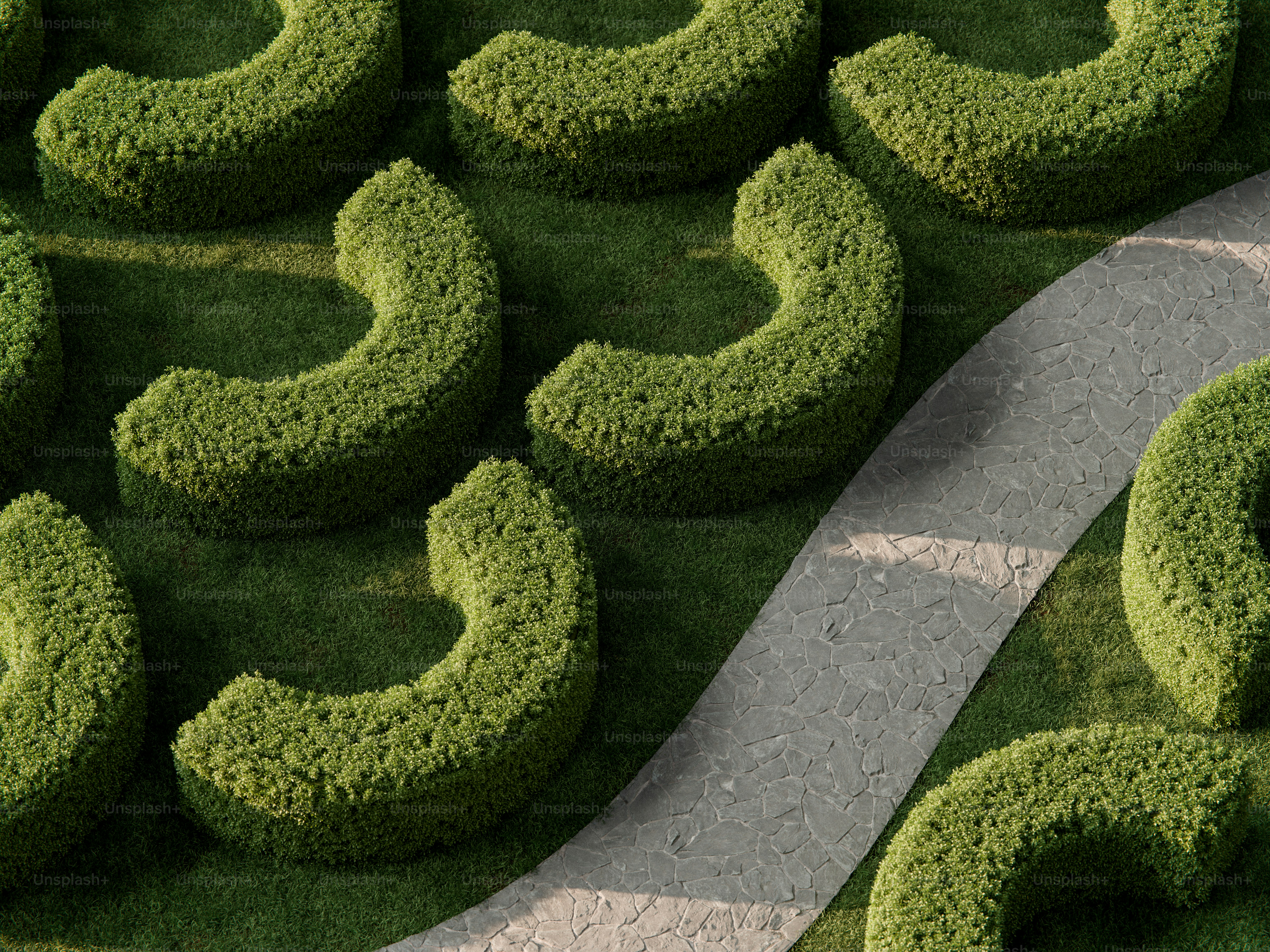 Crescent shaped hedges on a green lawn beside a stone garden path