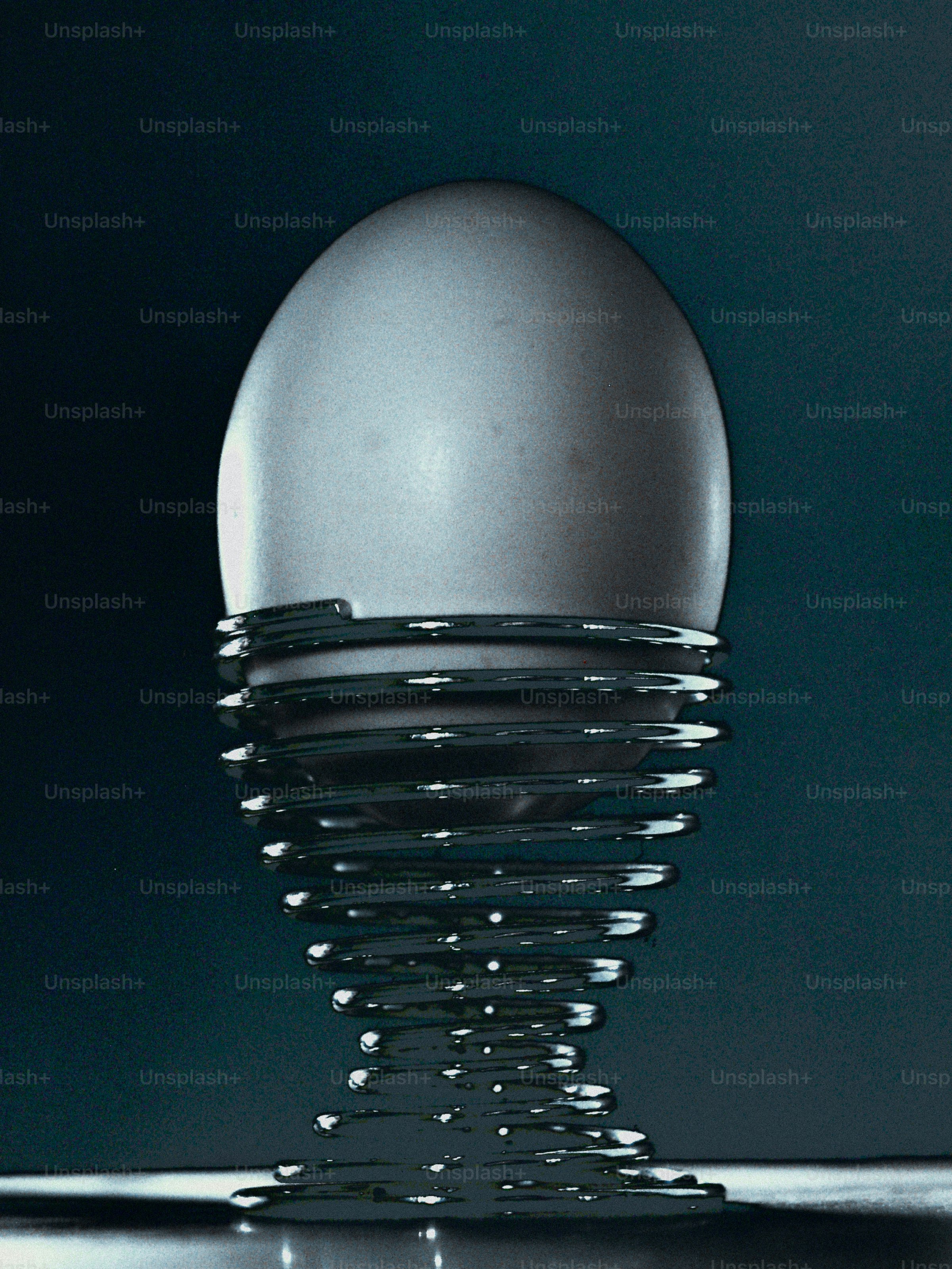 A single white egg in a coiled metal wire egg cup