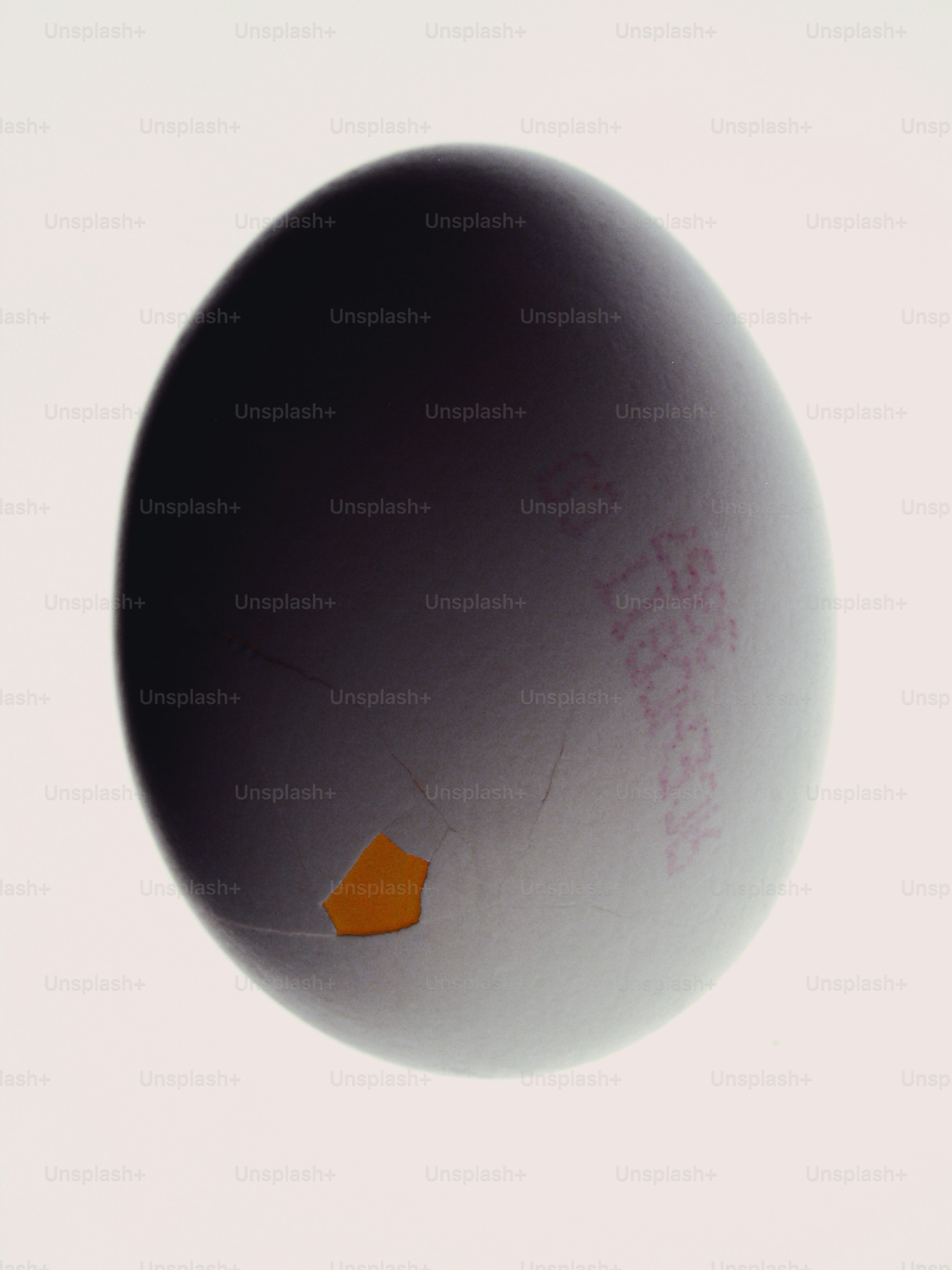 A single white egg with a small crack and red ink markings