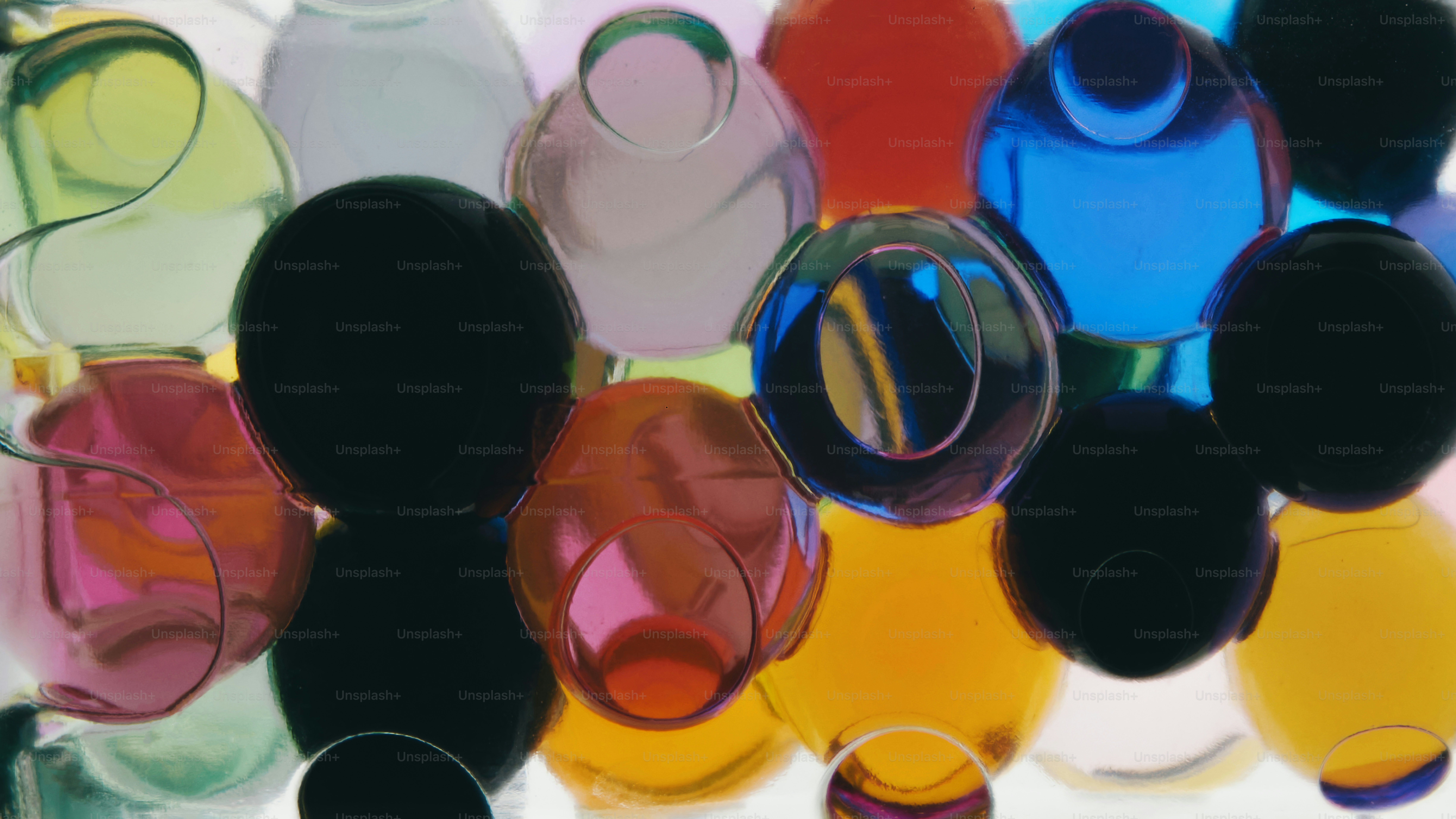 A cluster of translucent colorful water beads in shades of blue, yellow, and pink