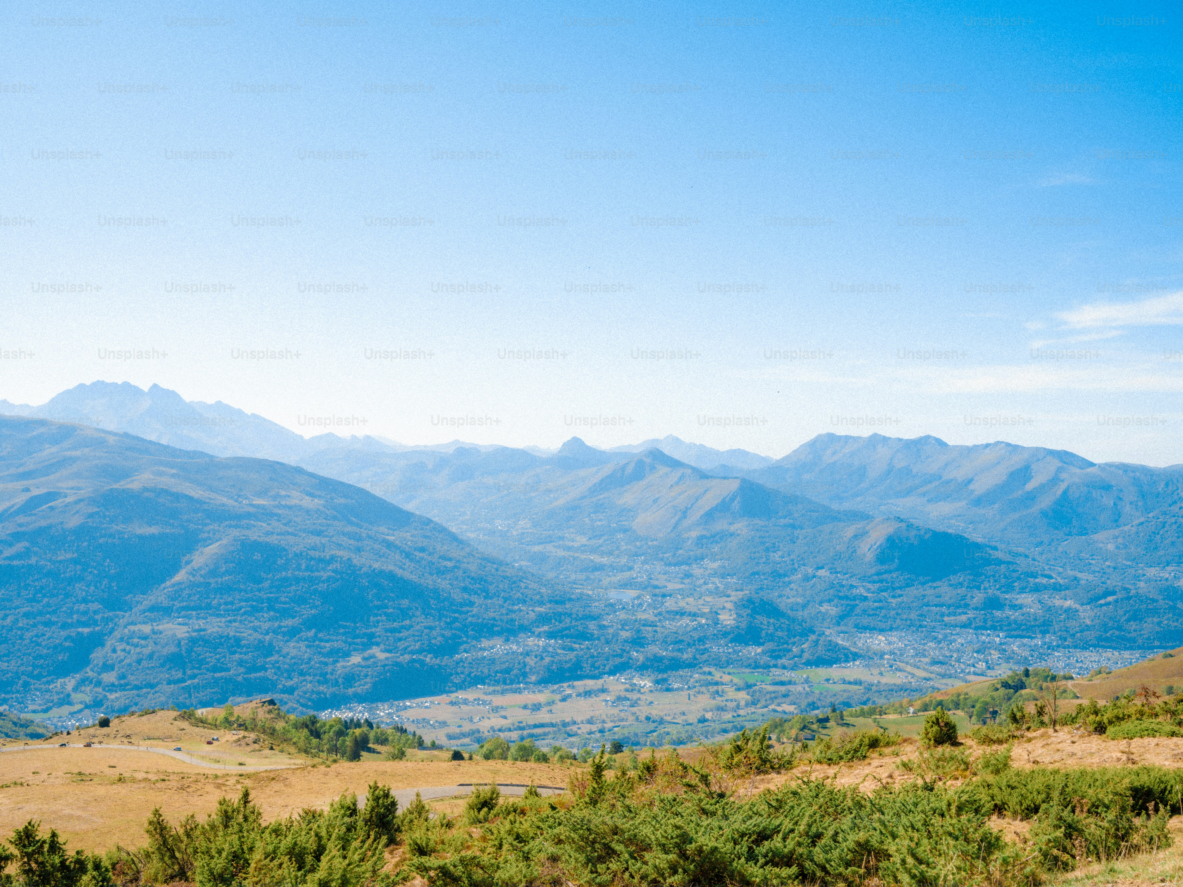 A wide valley with a town nestled between rolling blue mountain ranges