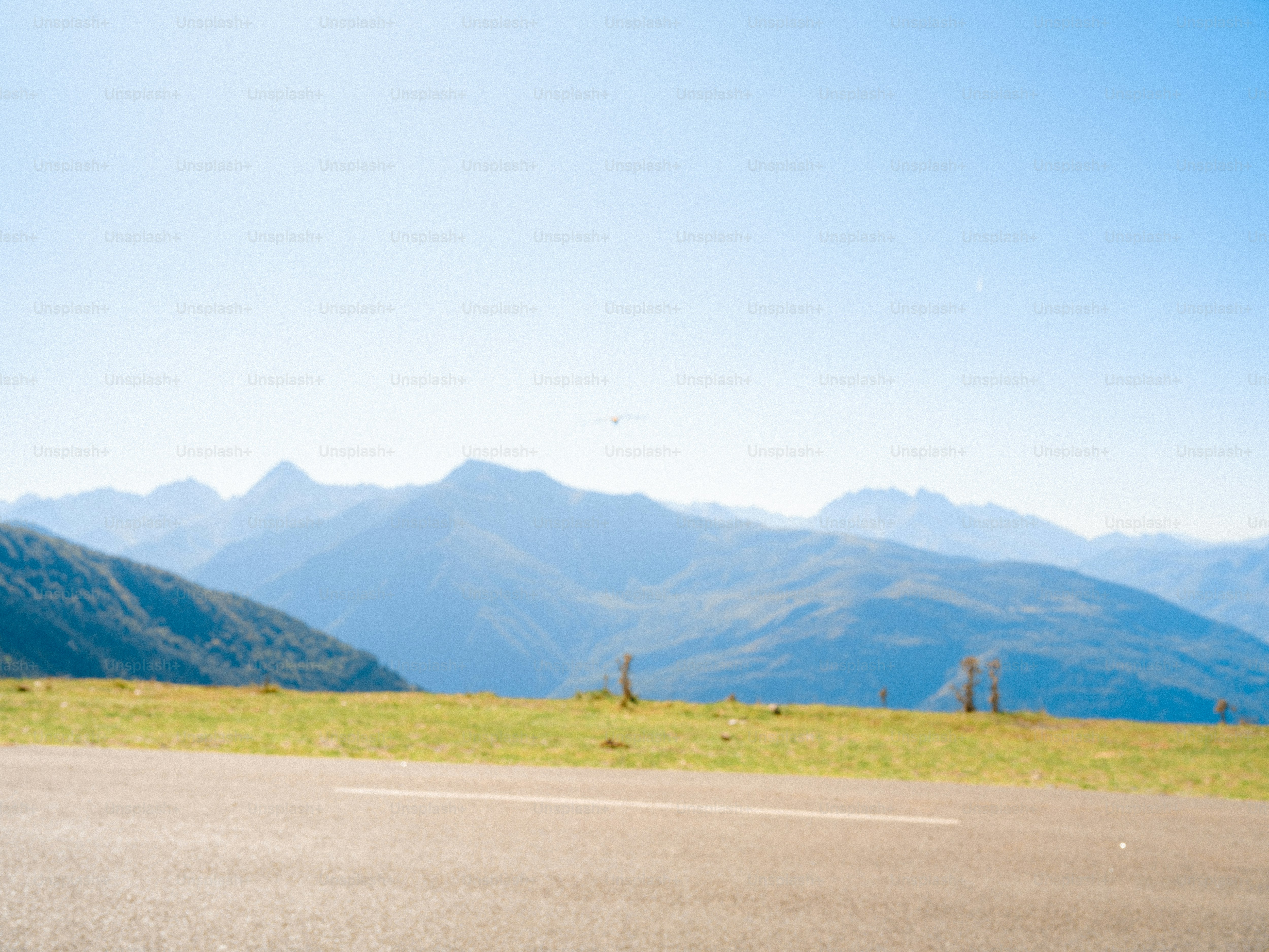 An asphalt road in the foreground with hazy blue mountains in the distance