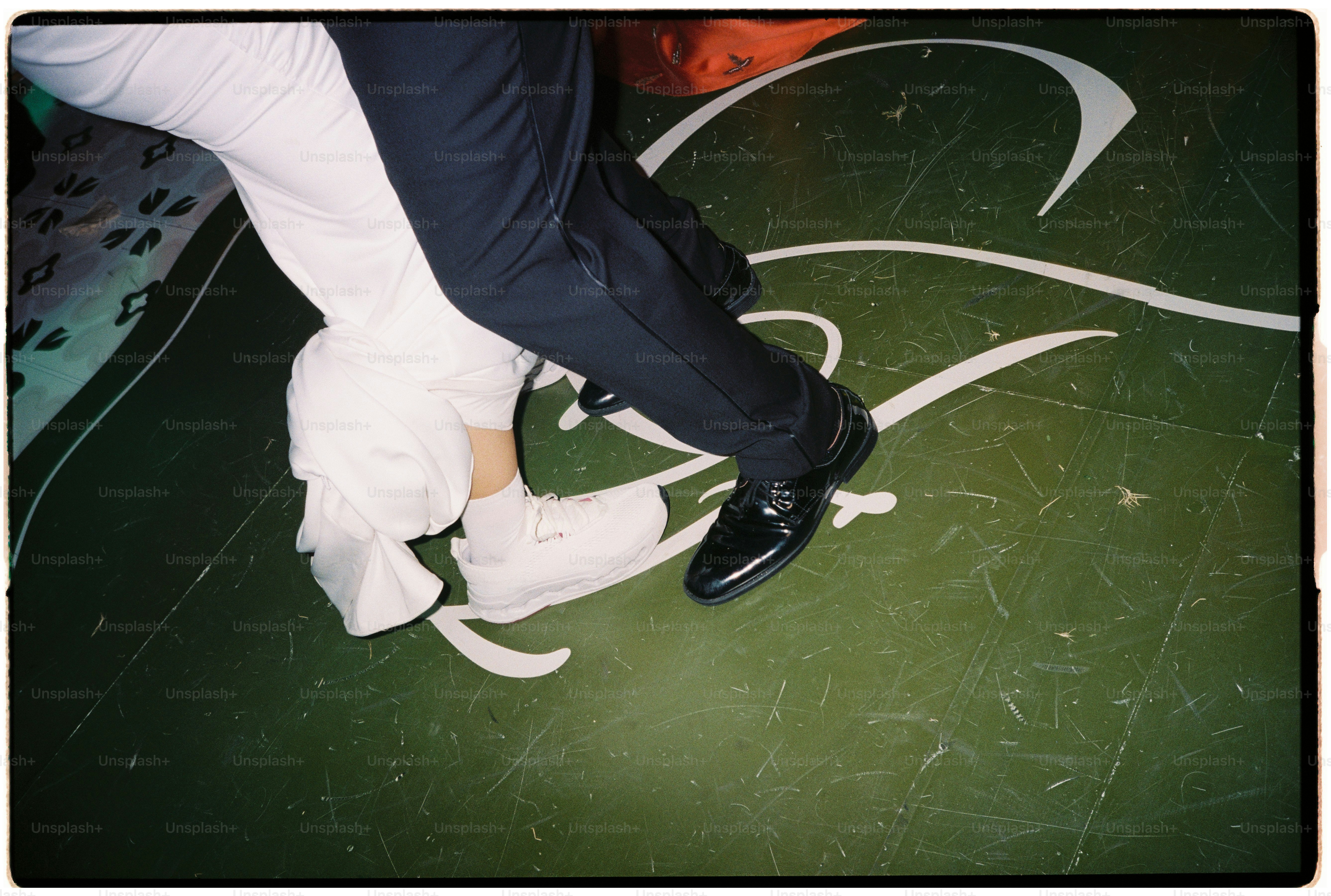 Two people dancing on a green floor with white markings