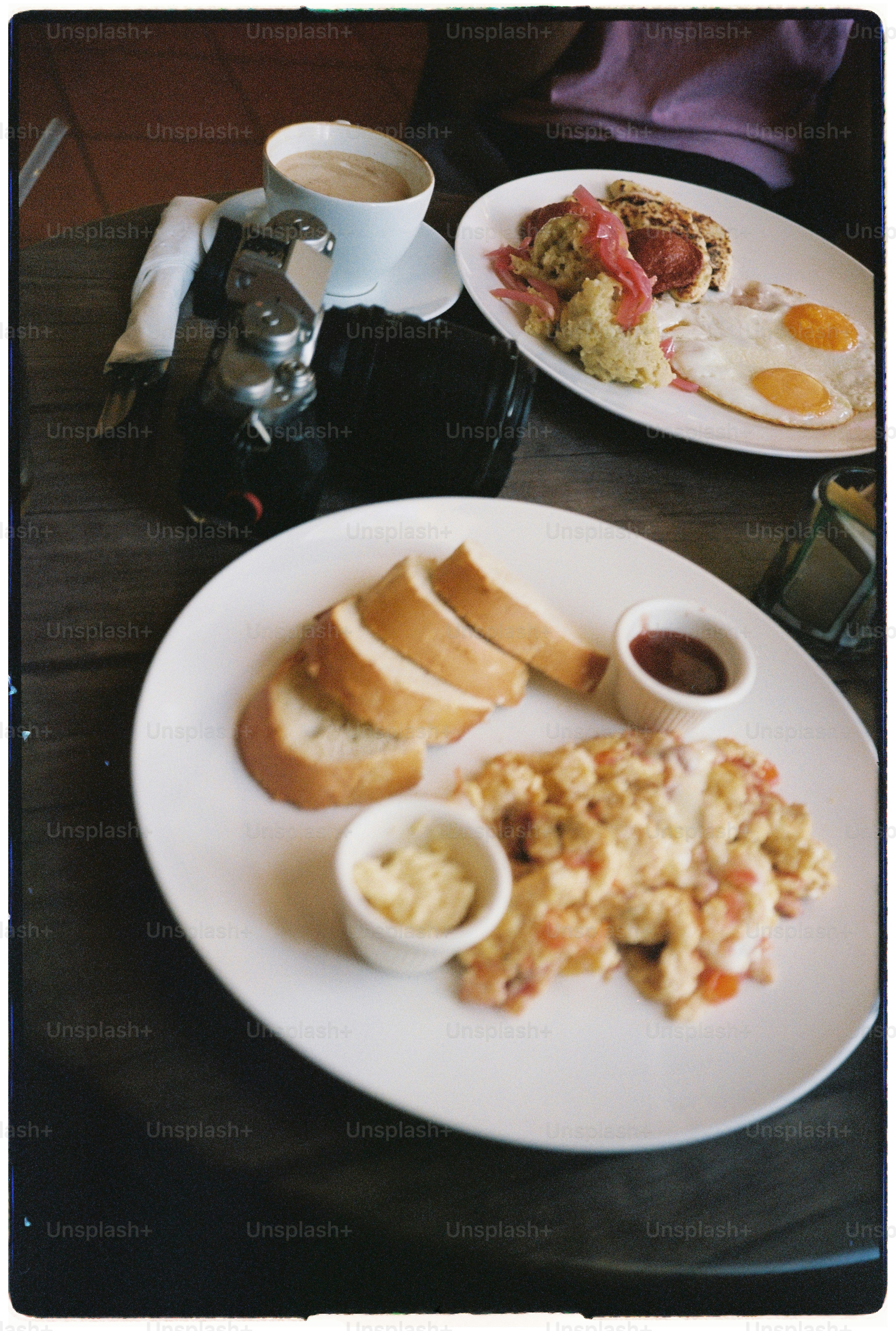 Scrambled eggs with bread and butter on a plate next to a camera