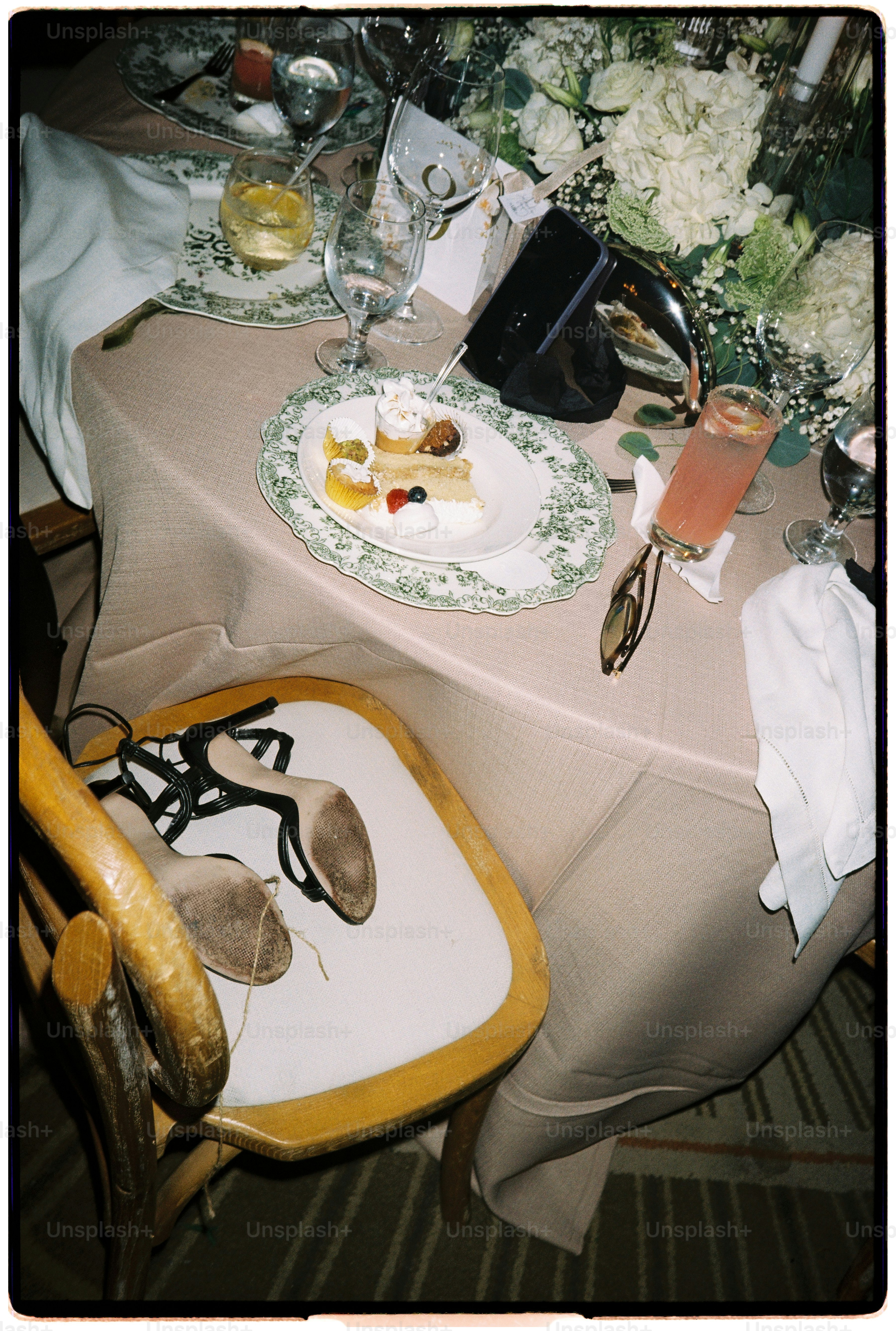 Black high-heeled sandals on a wooden chair beside a table set for a celebration