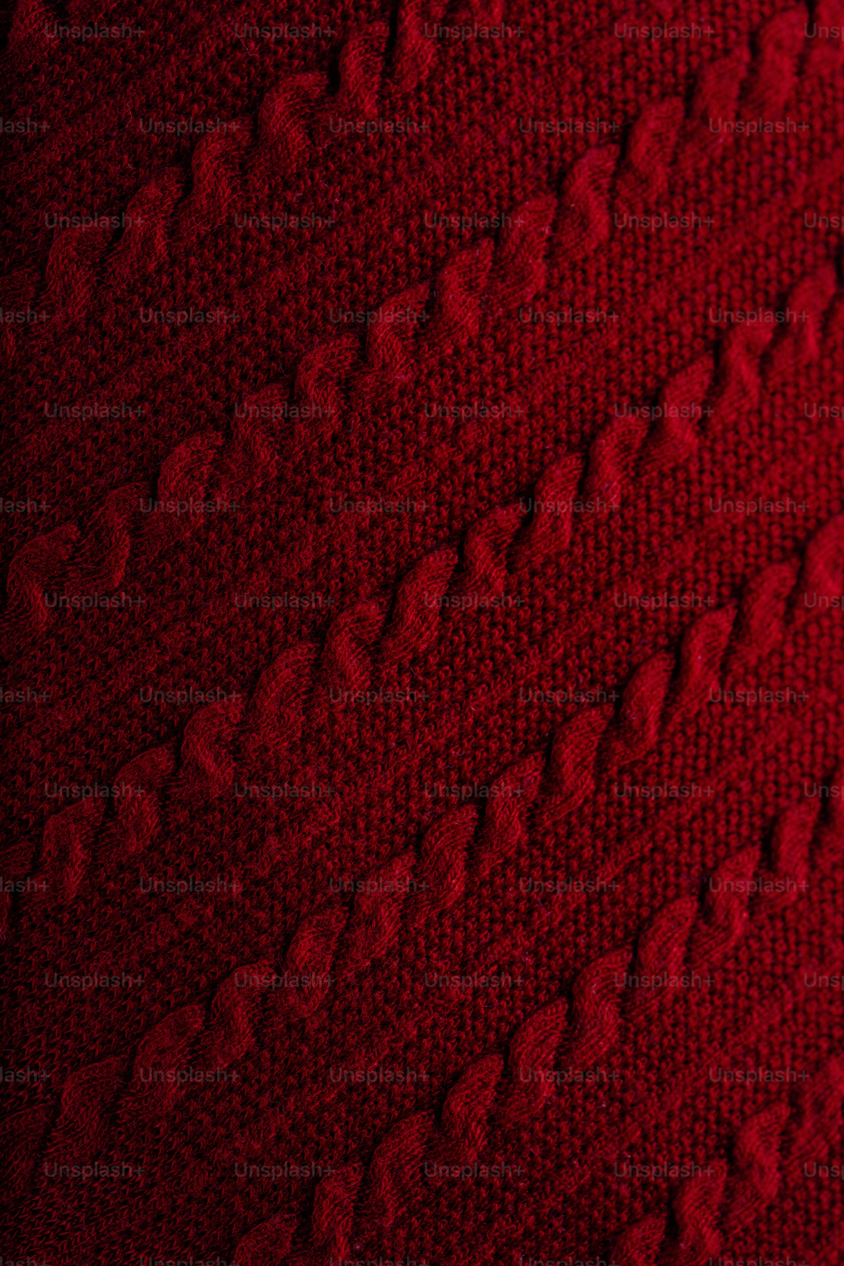 Deep red knitted fabric with a diagonal cable knit pattern