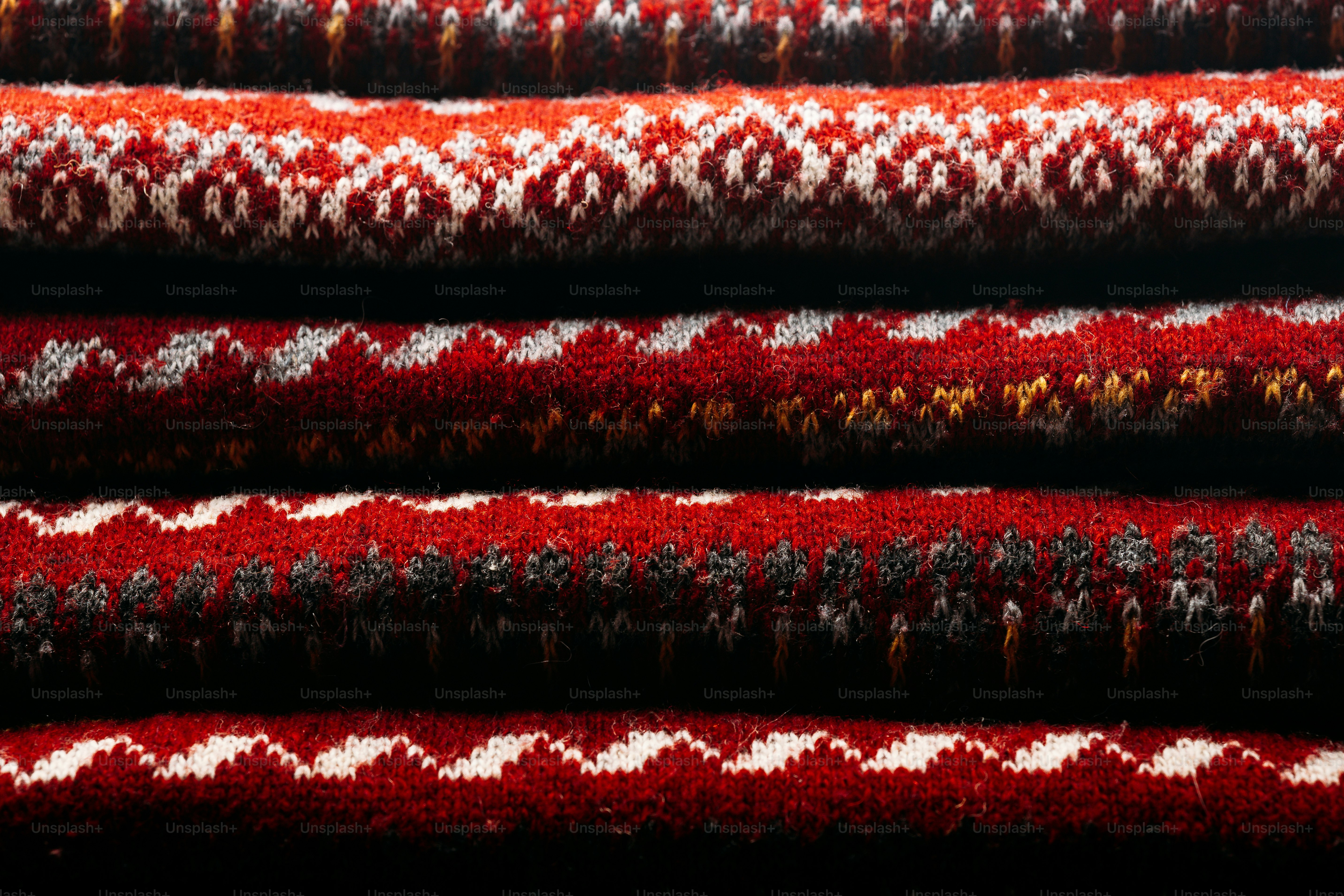 Stacked layers of red and white knitted fabric with intricate geometric patterns