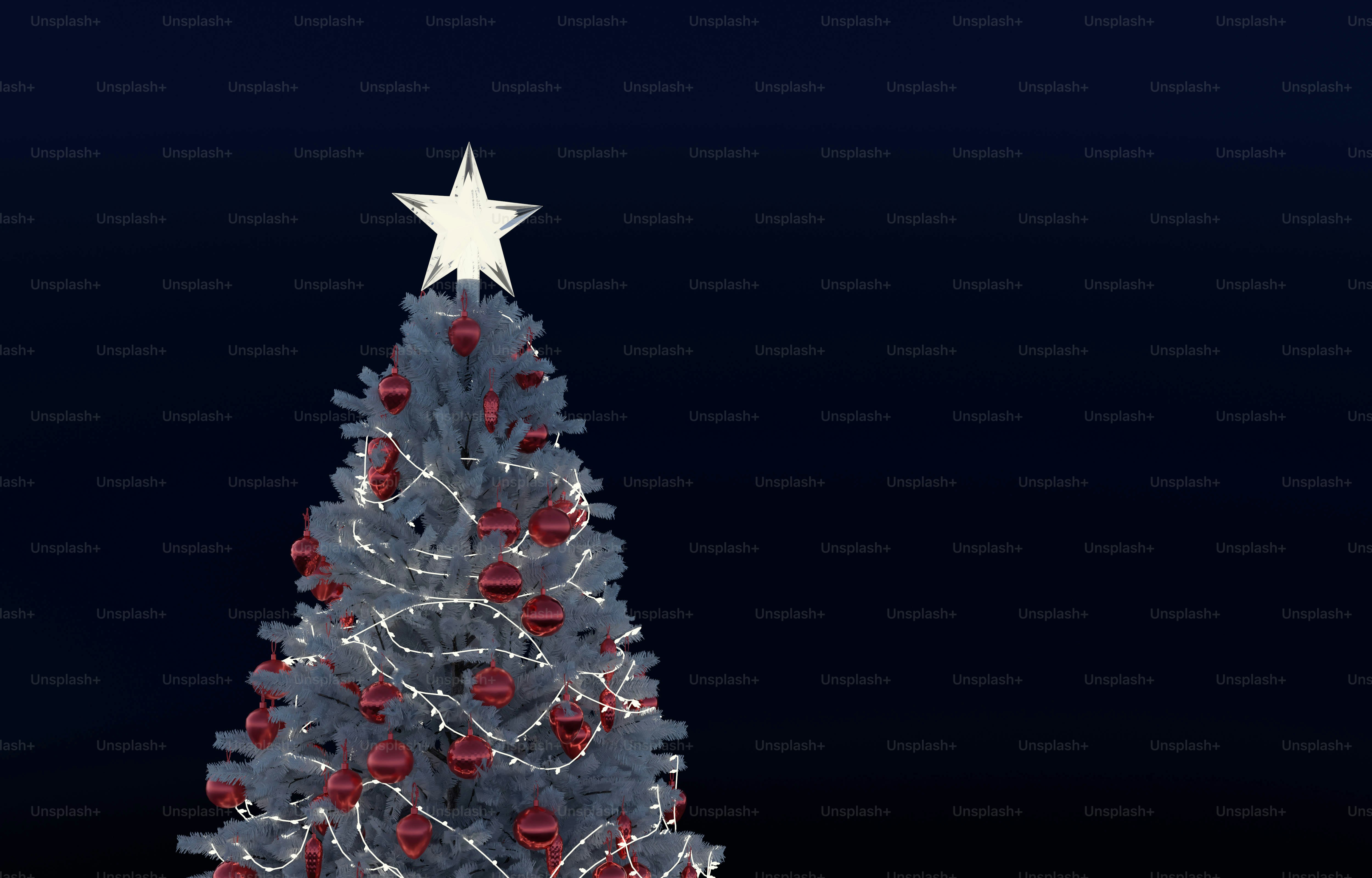 A white Christmas tree decorated with red ornaments and string lights against dark blue