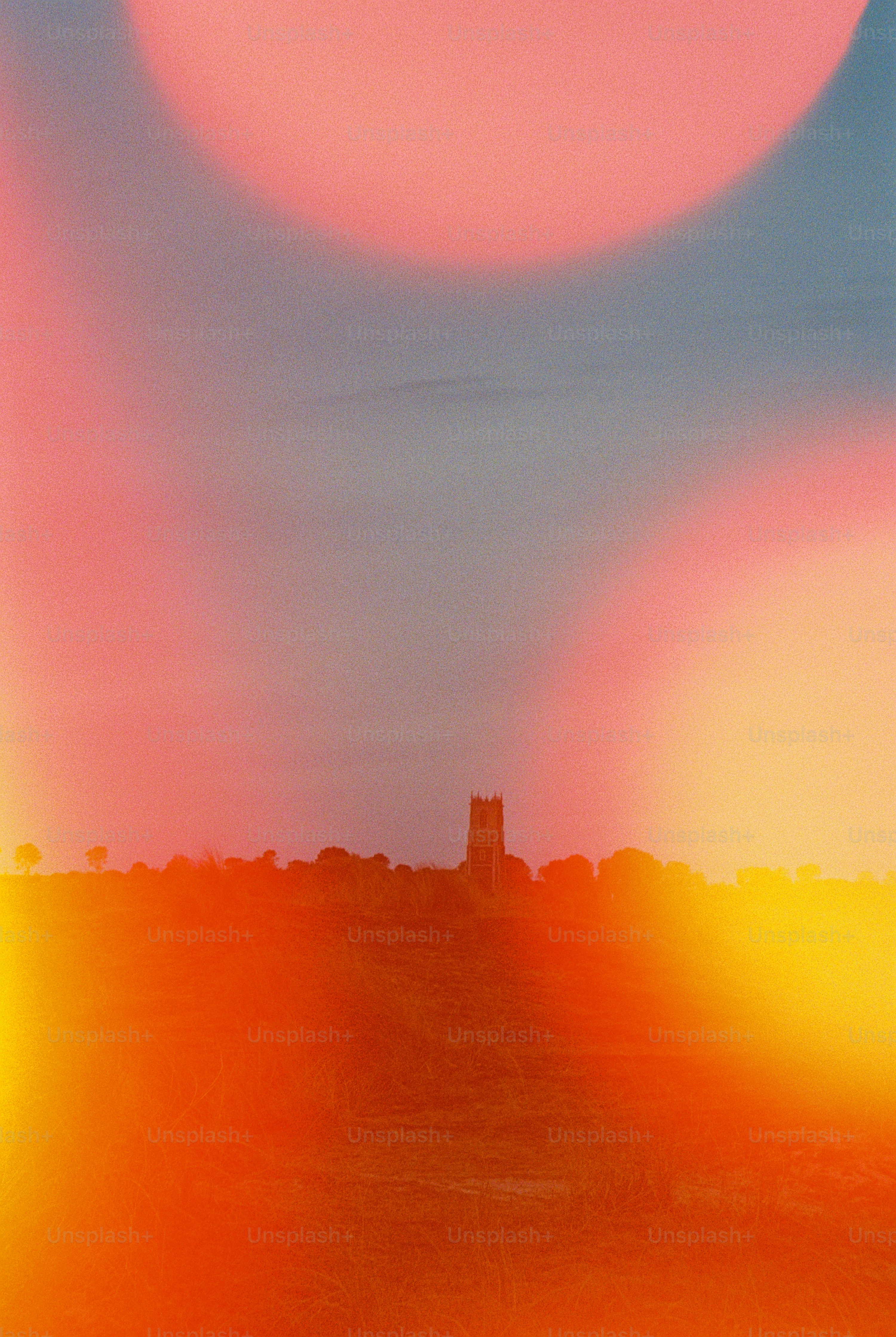A church tower silhouette against a vibrant orange and pink gradient sky