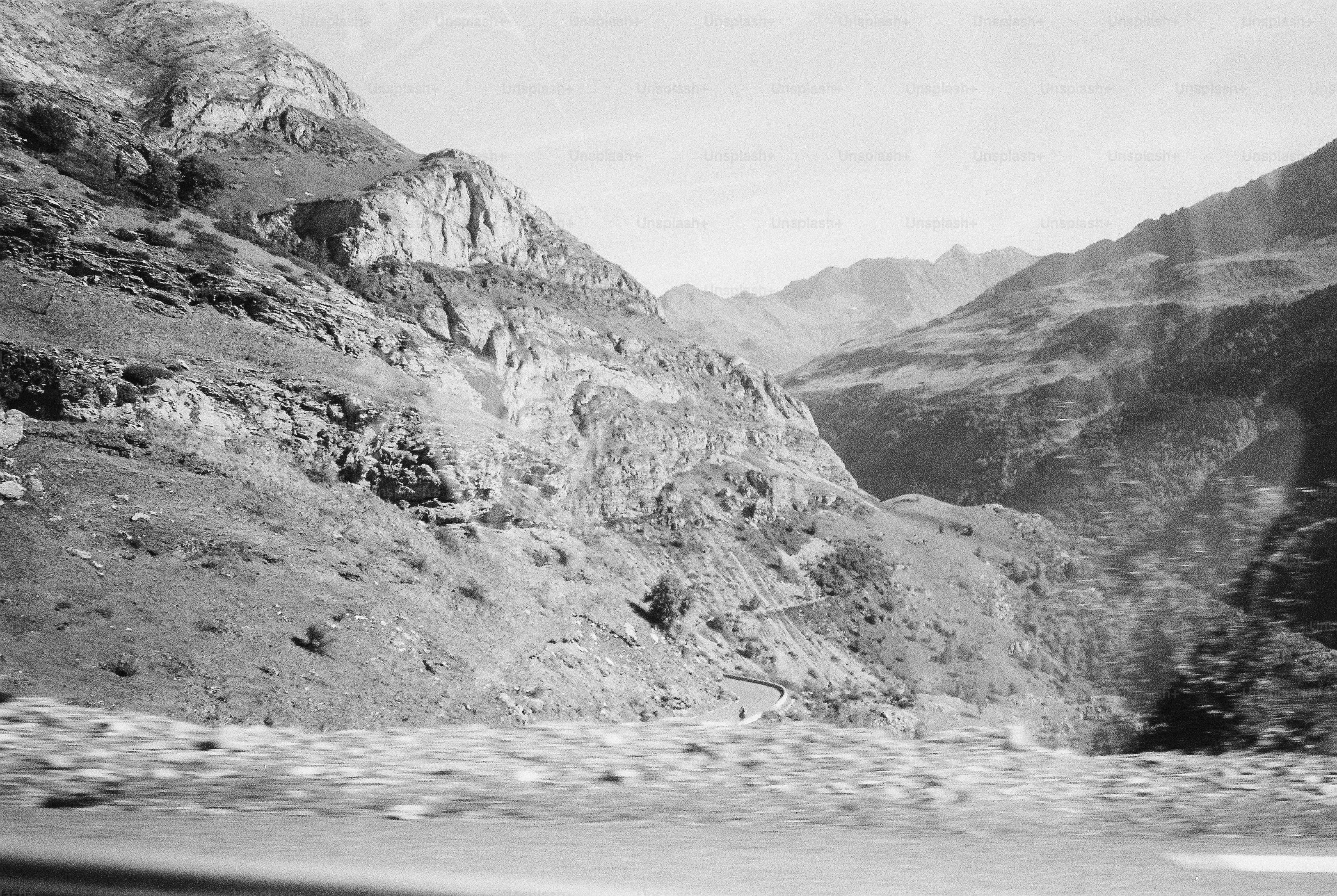A winding road through a rocky mountain valley in black and white