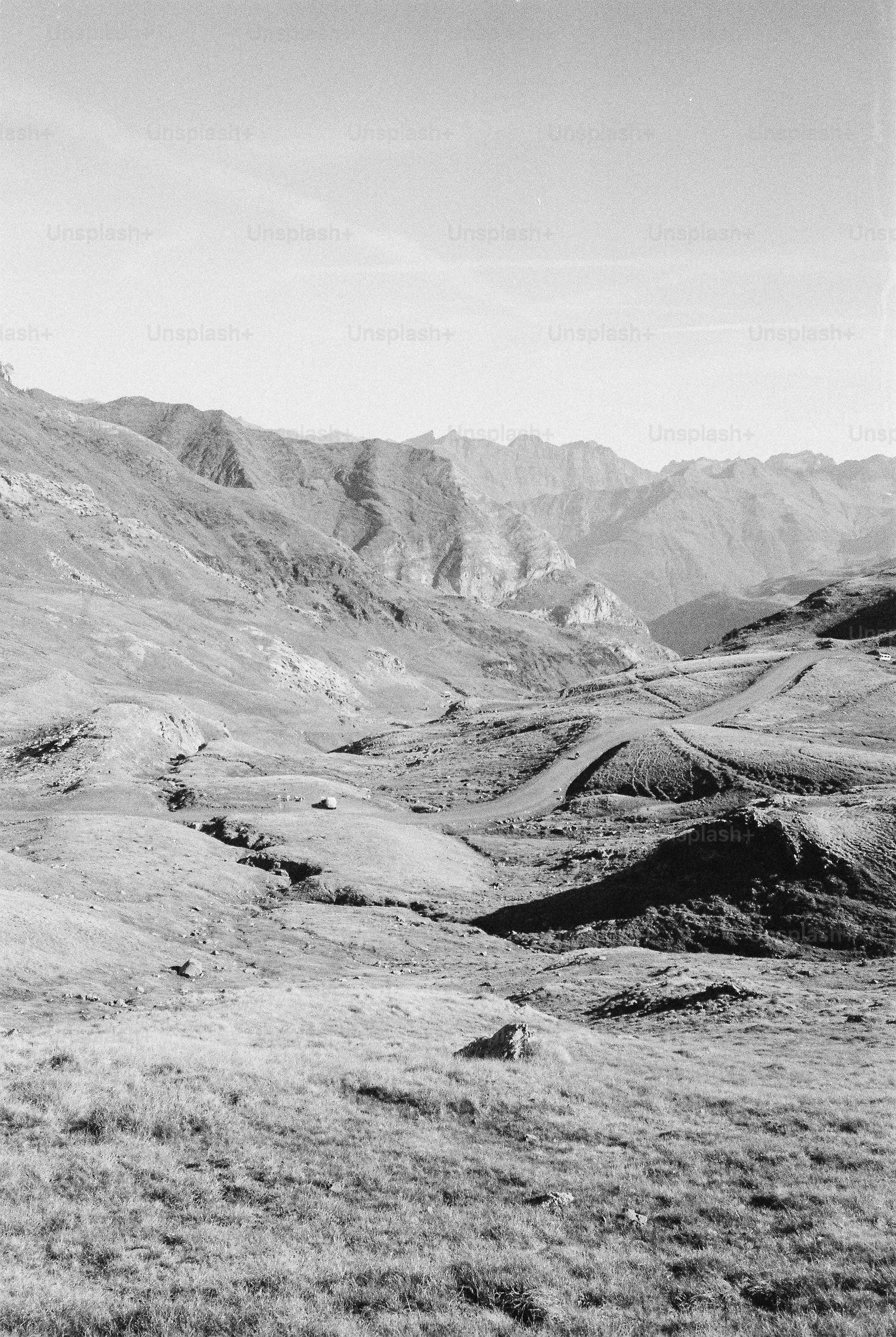 A winding dirt road through a vast mountain valley under a clear sky