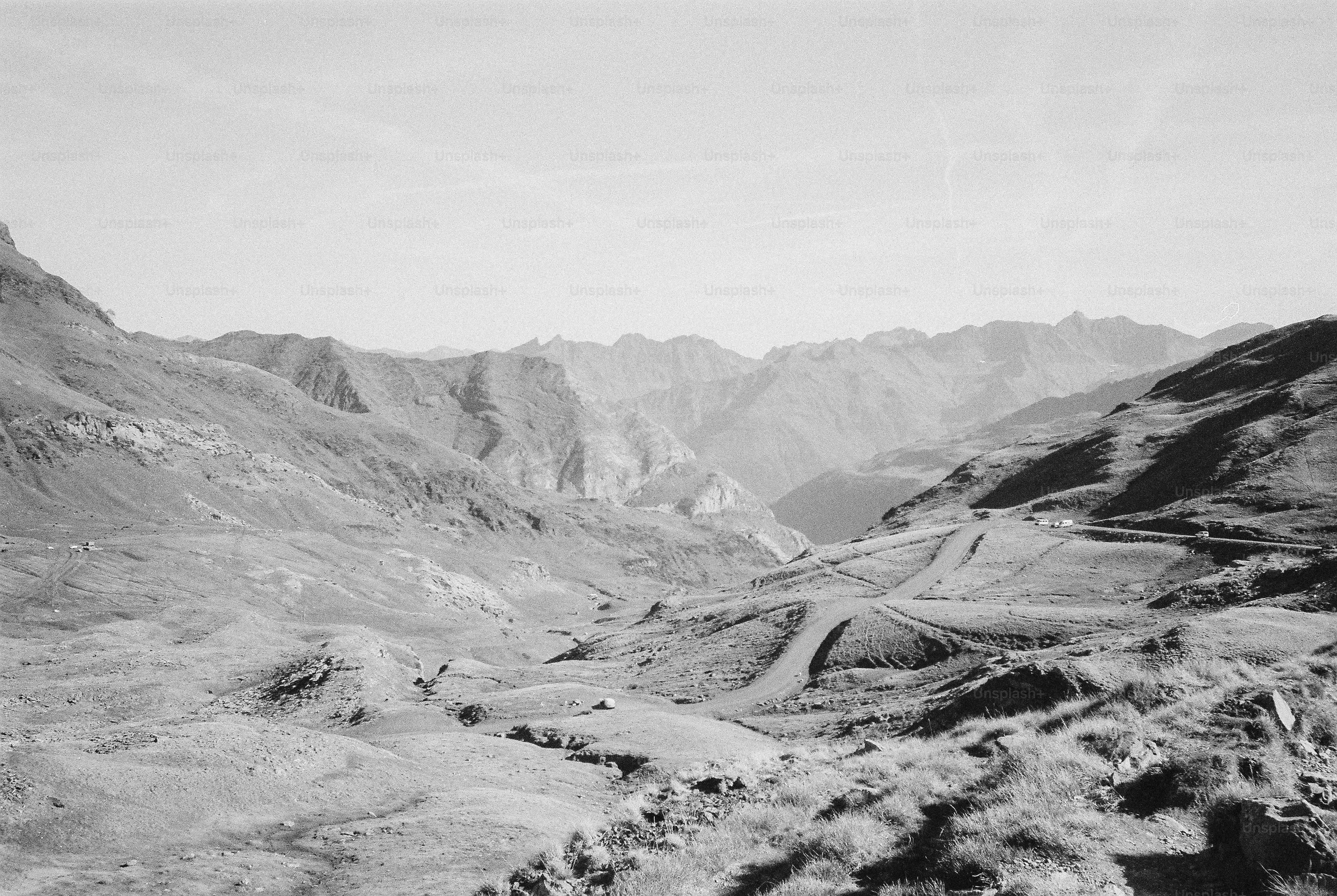 A winding mountain road through a vast valley with rugged peaks in the distance