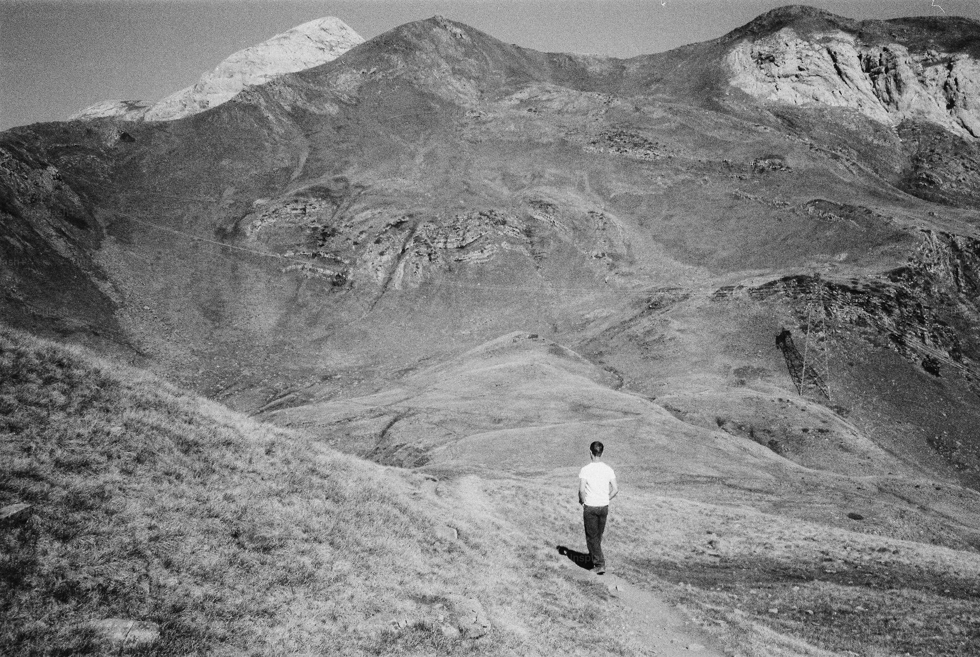 A person in a white t-shirt walking along a mountain trail