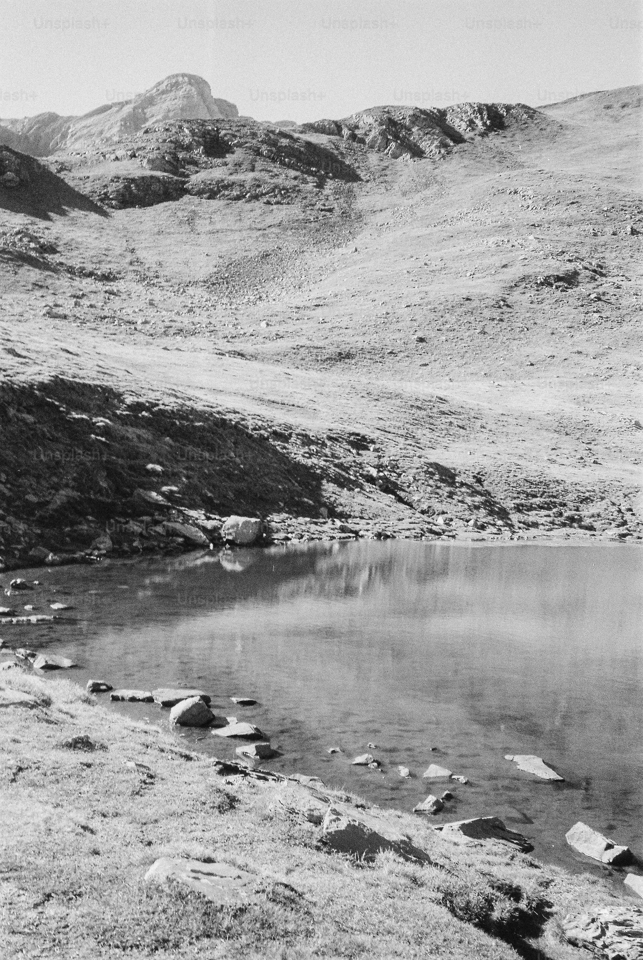 A black and white view of a mountain lake surrounded by rocky slopes