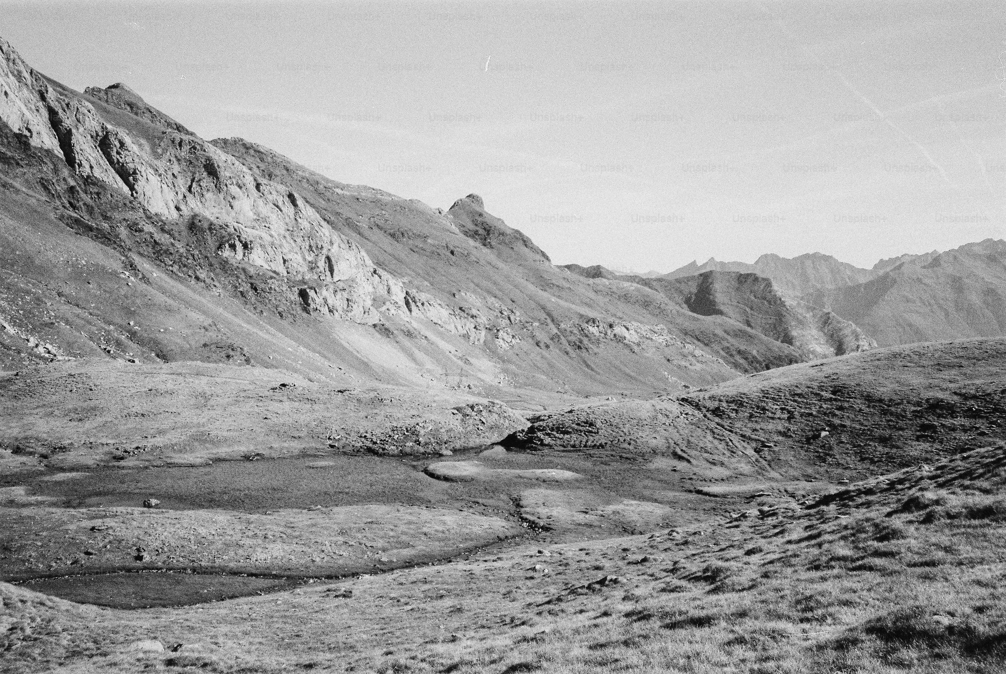 A small pond in a grassy mountain valley beneath rocky slopes