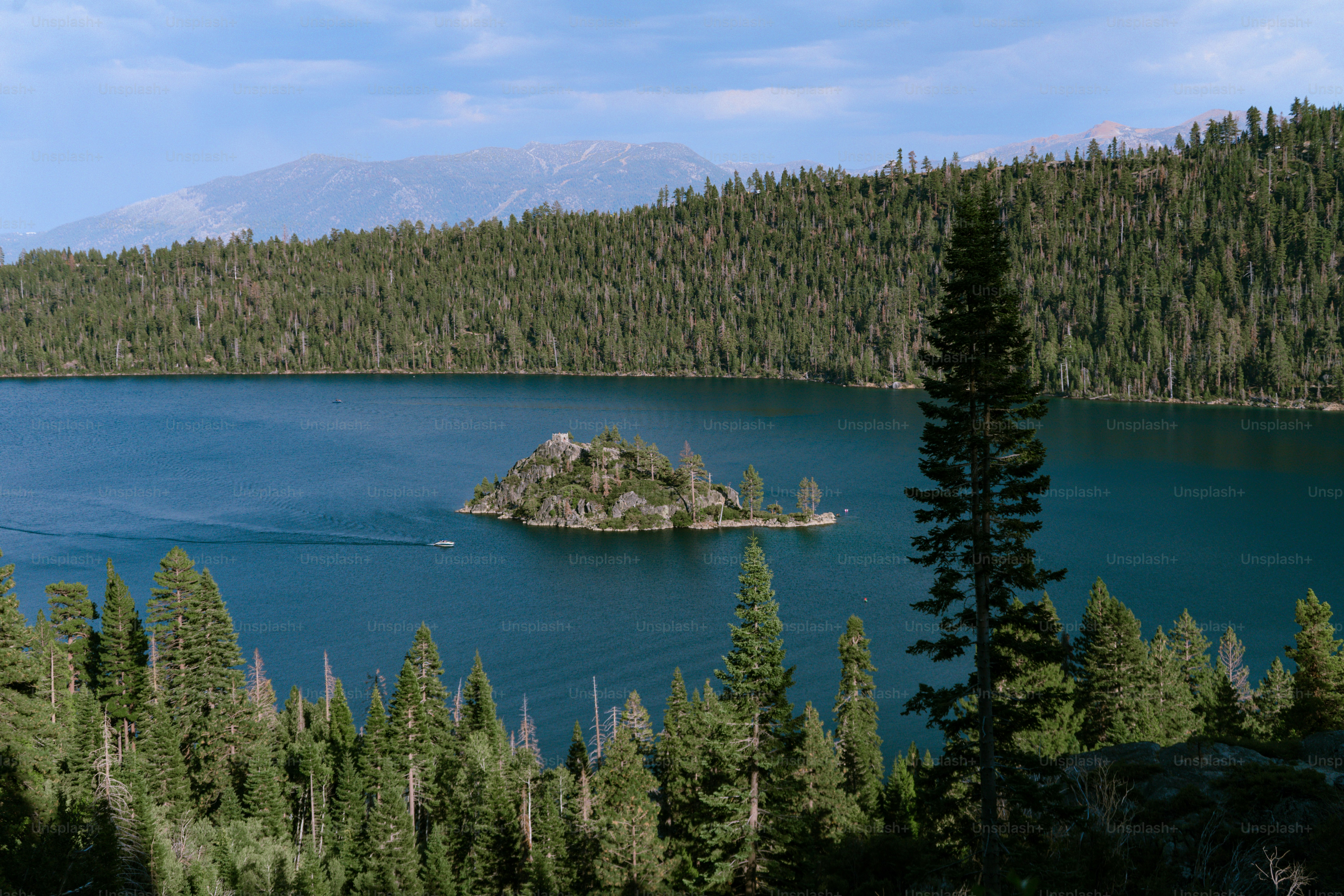 A small rocky island with trees in the middle of a deep blue lake