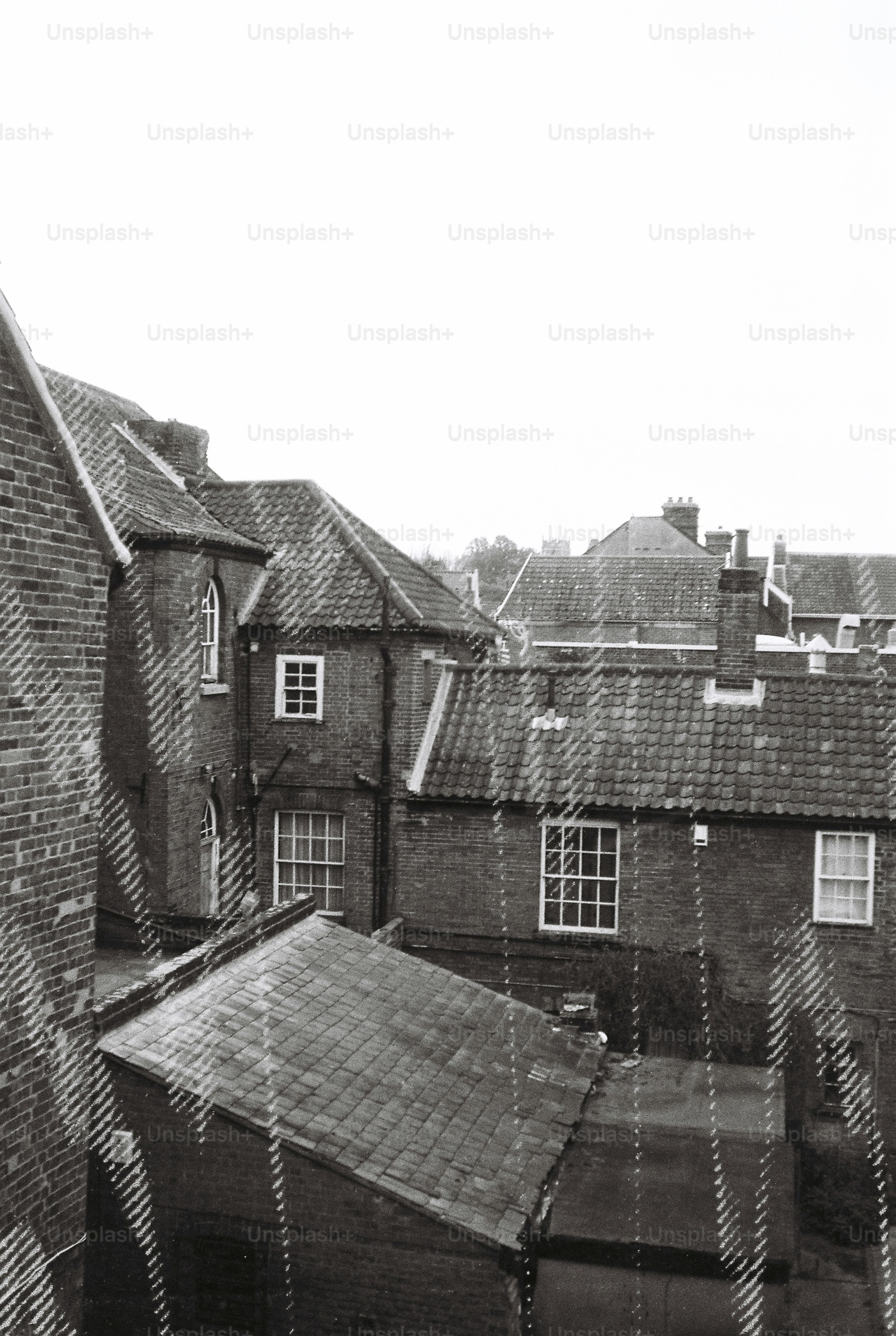Black and white view of brick buildings with tiled roofs on a rainy day