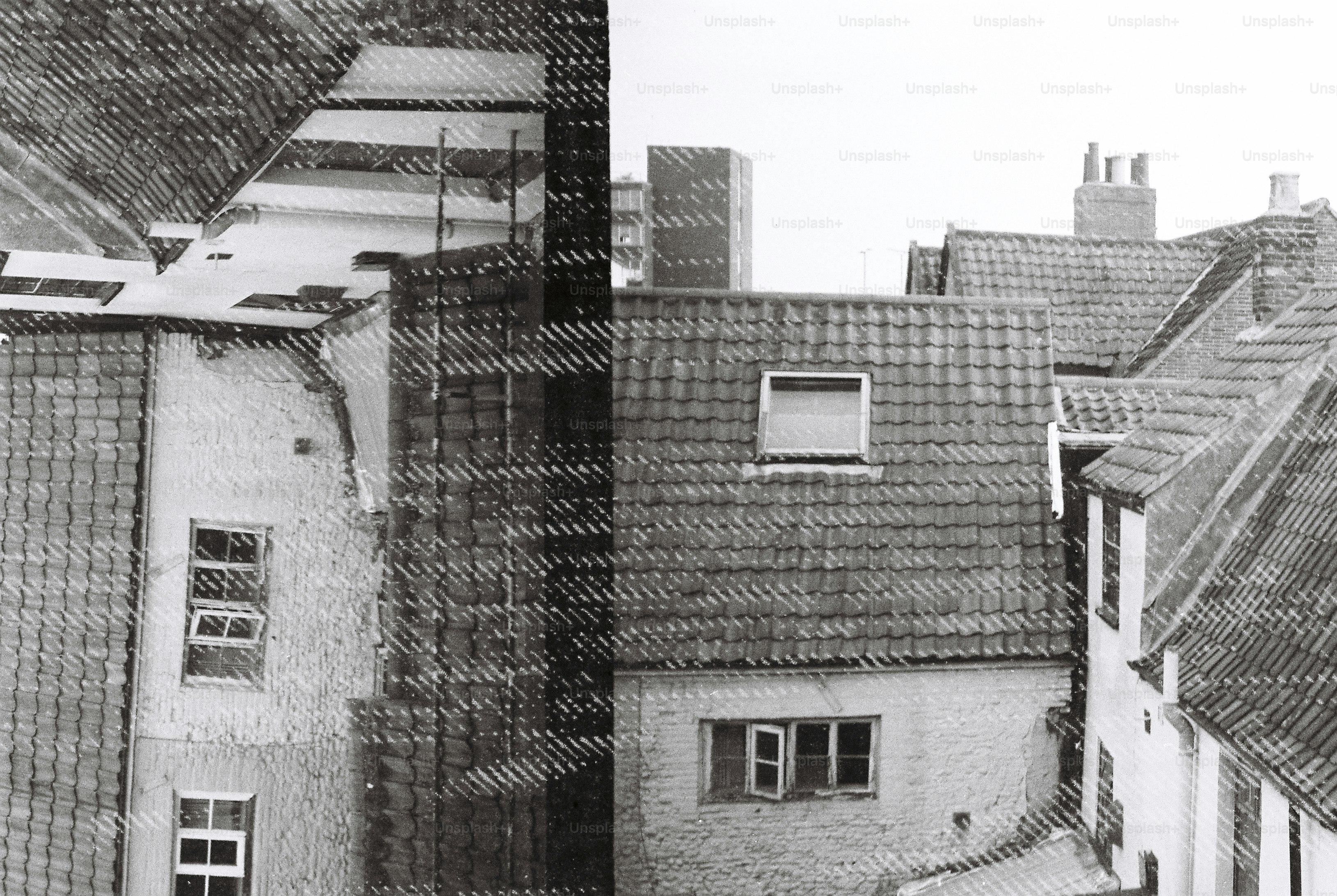 A double exposure of tiled rooftops and building facades in black and white