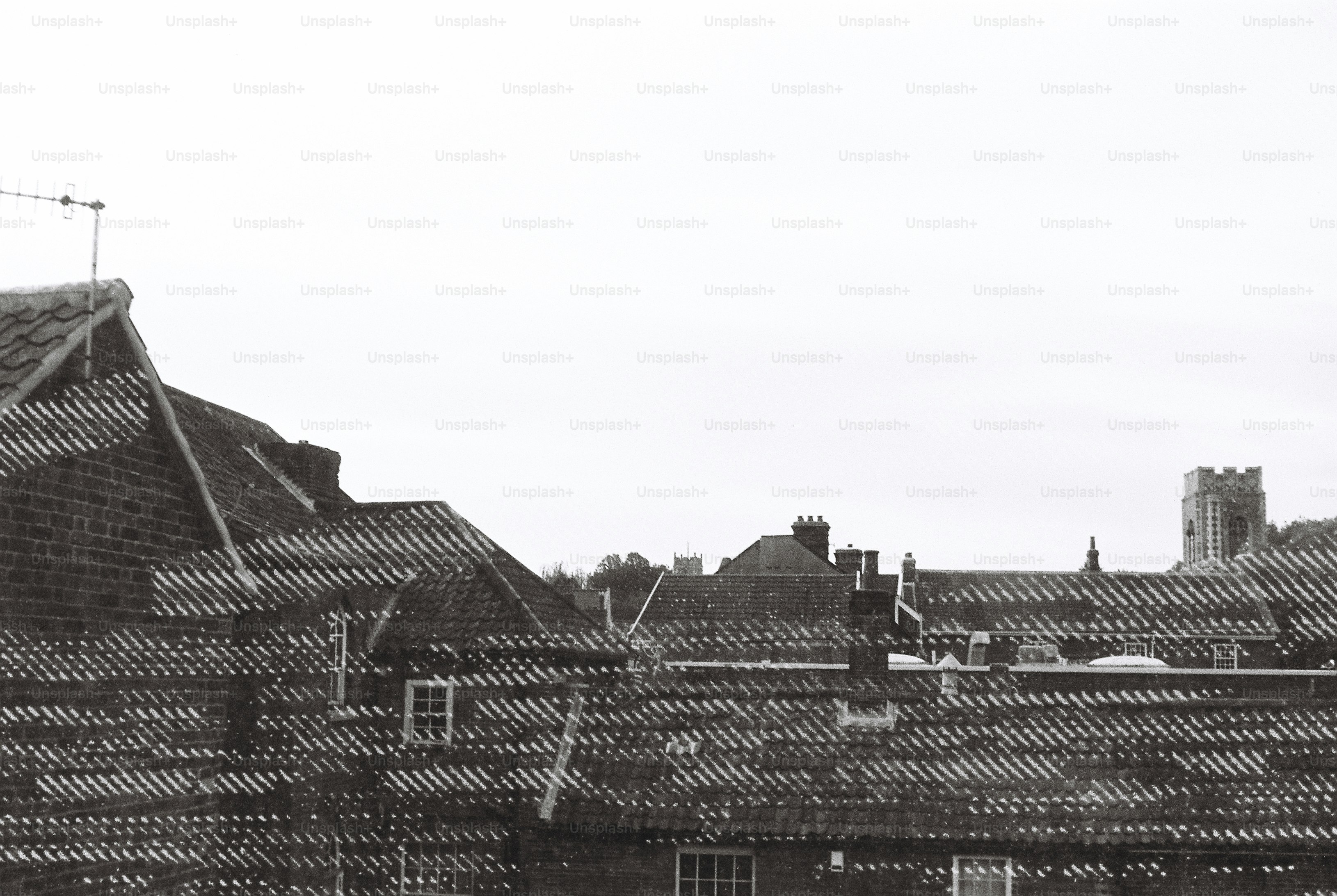 Tiled rooftops of brick buildings with a church tower in the distance
