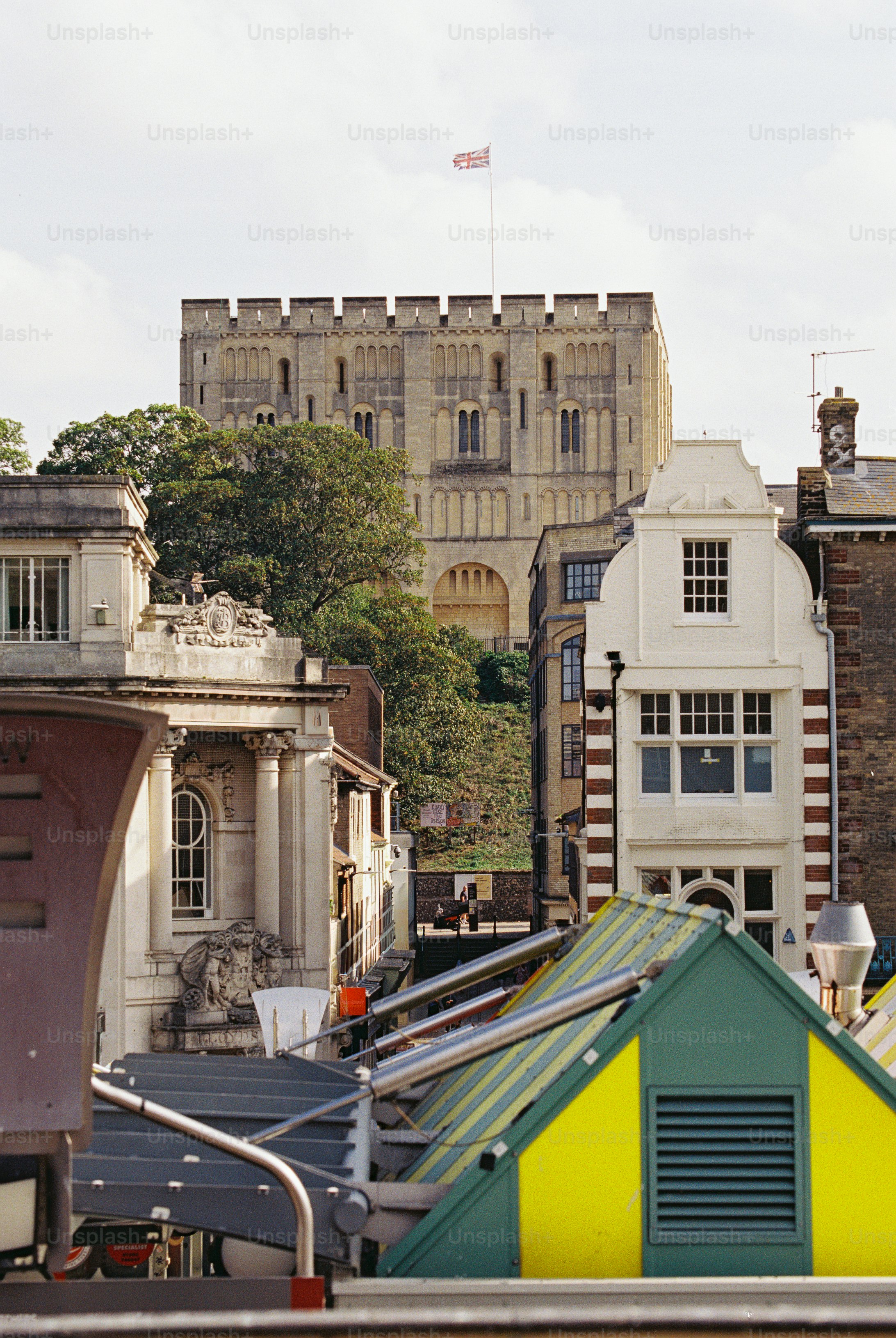 The Norman castle keep rising above city rooftops and a market in Norwich