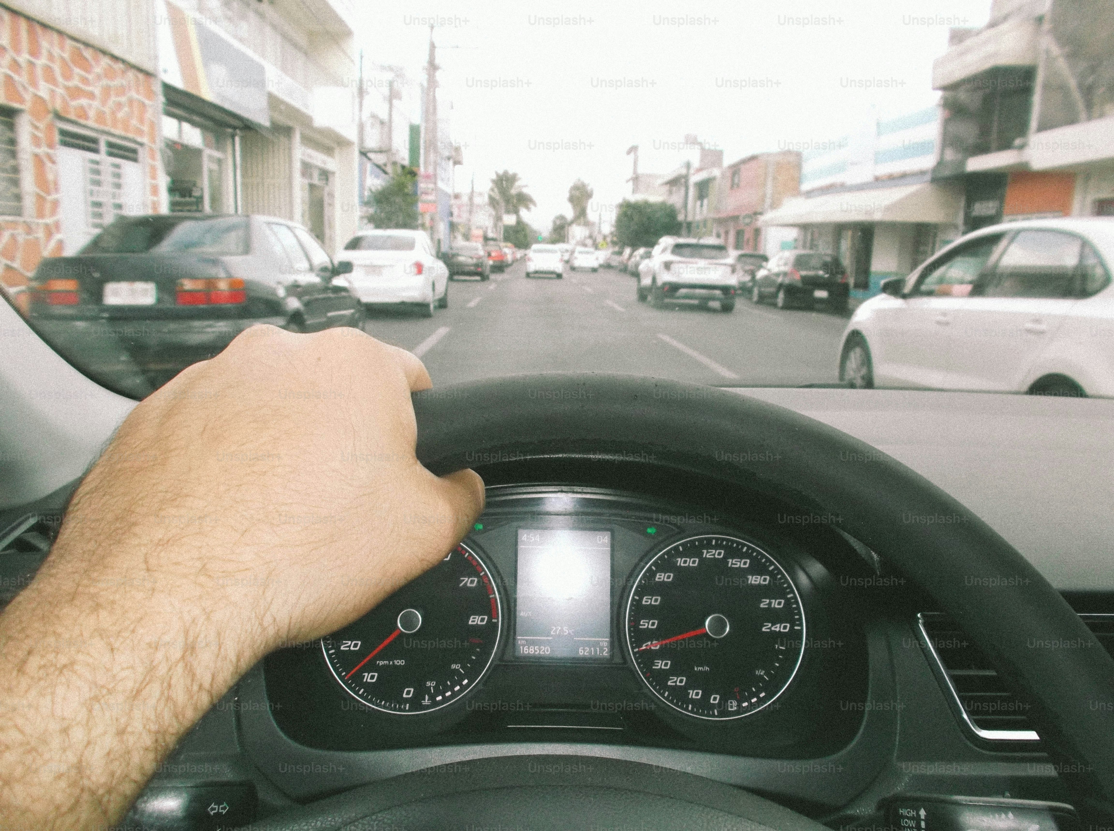 A person driving a car on a city street with other vehicles ahead