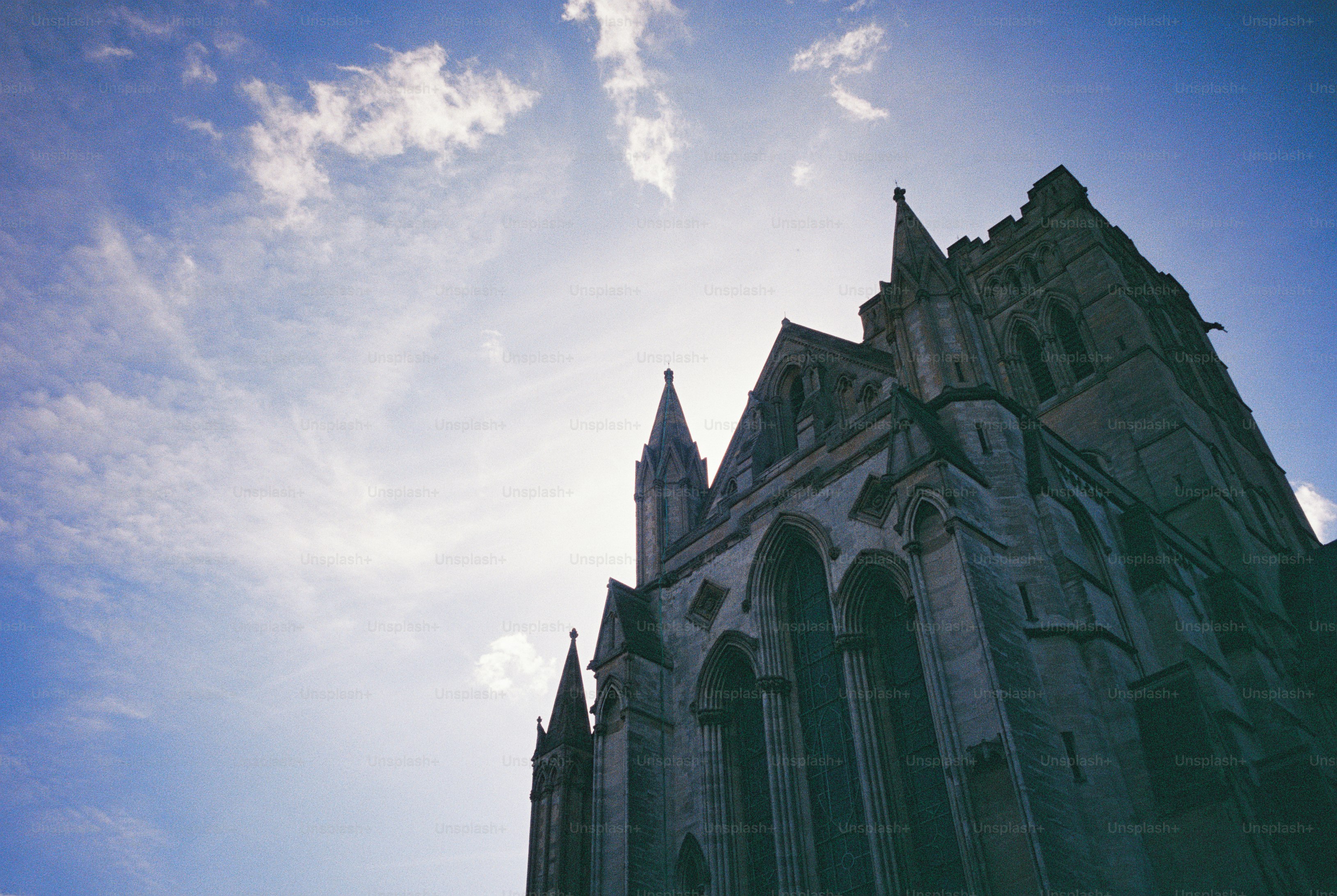 A stone Gothic cathedral with spires backlit by the sun in Norwich, United Kingdom