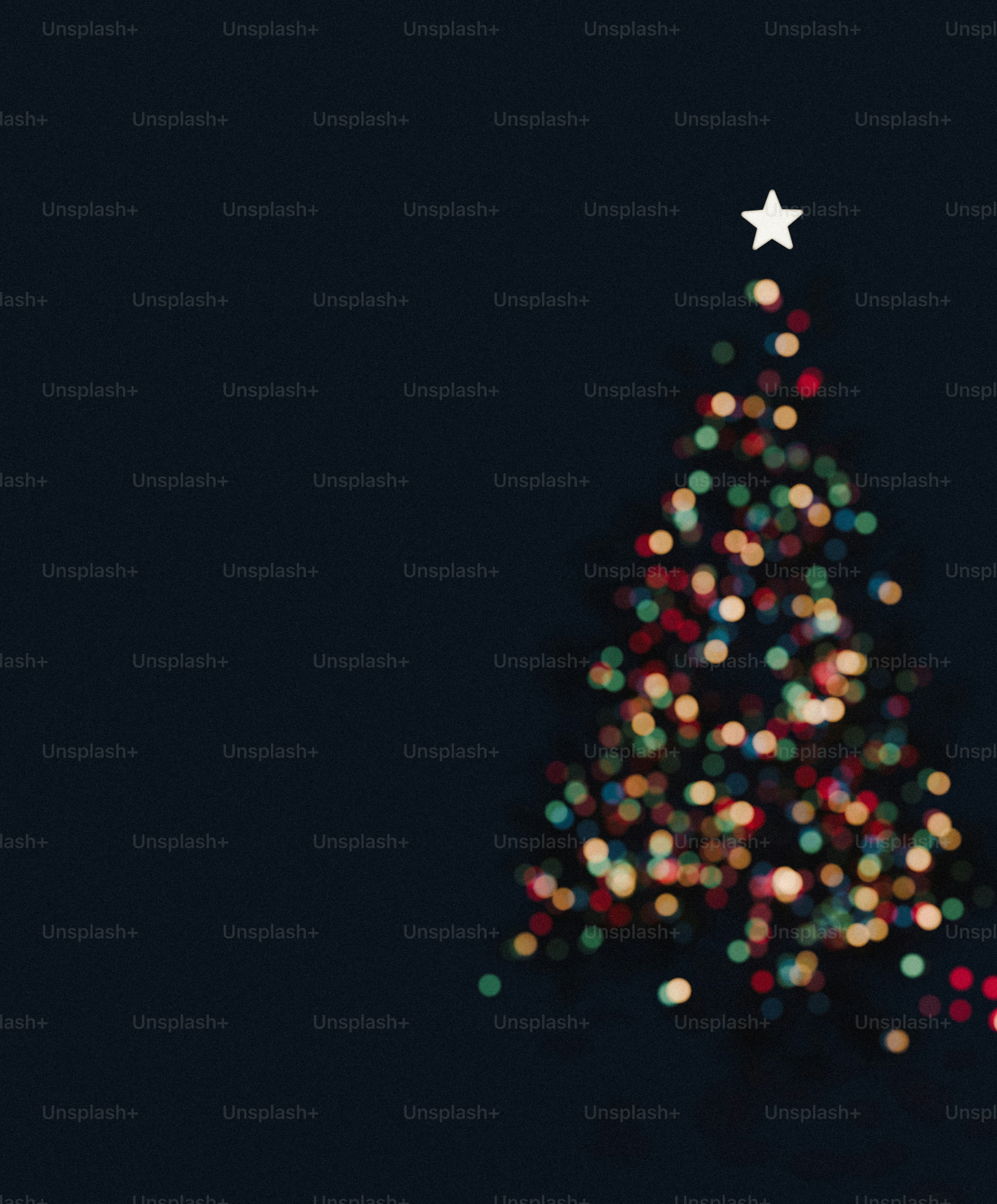 A white star atop a Christmas tree shape made of colorful bokeh lights