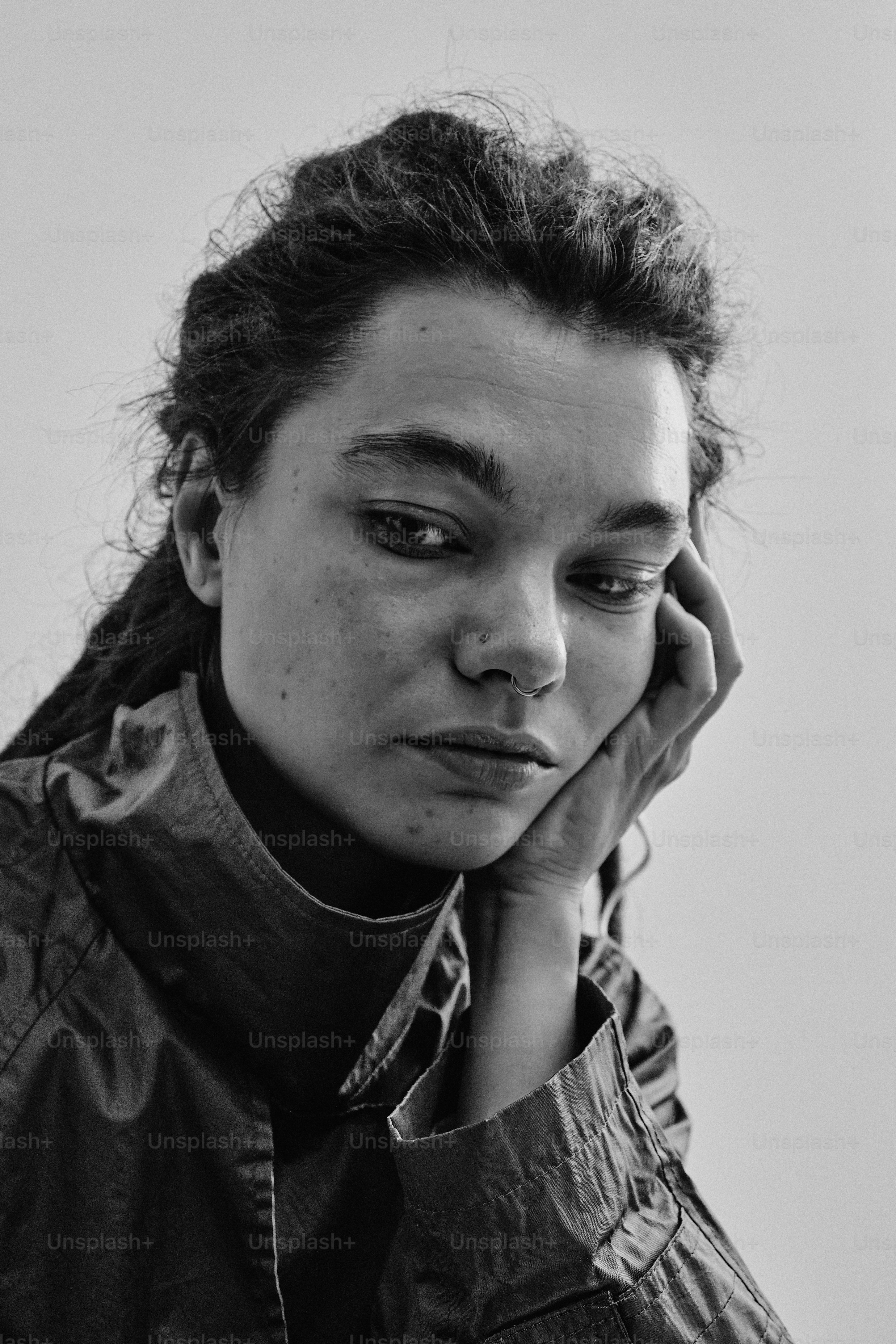 A person with a nose ring resting their chin on a hand