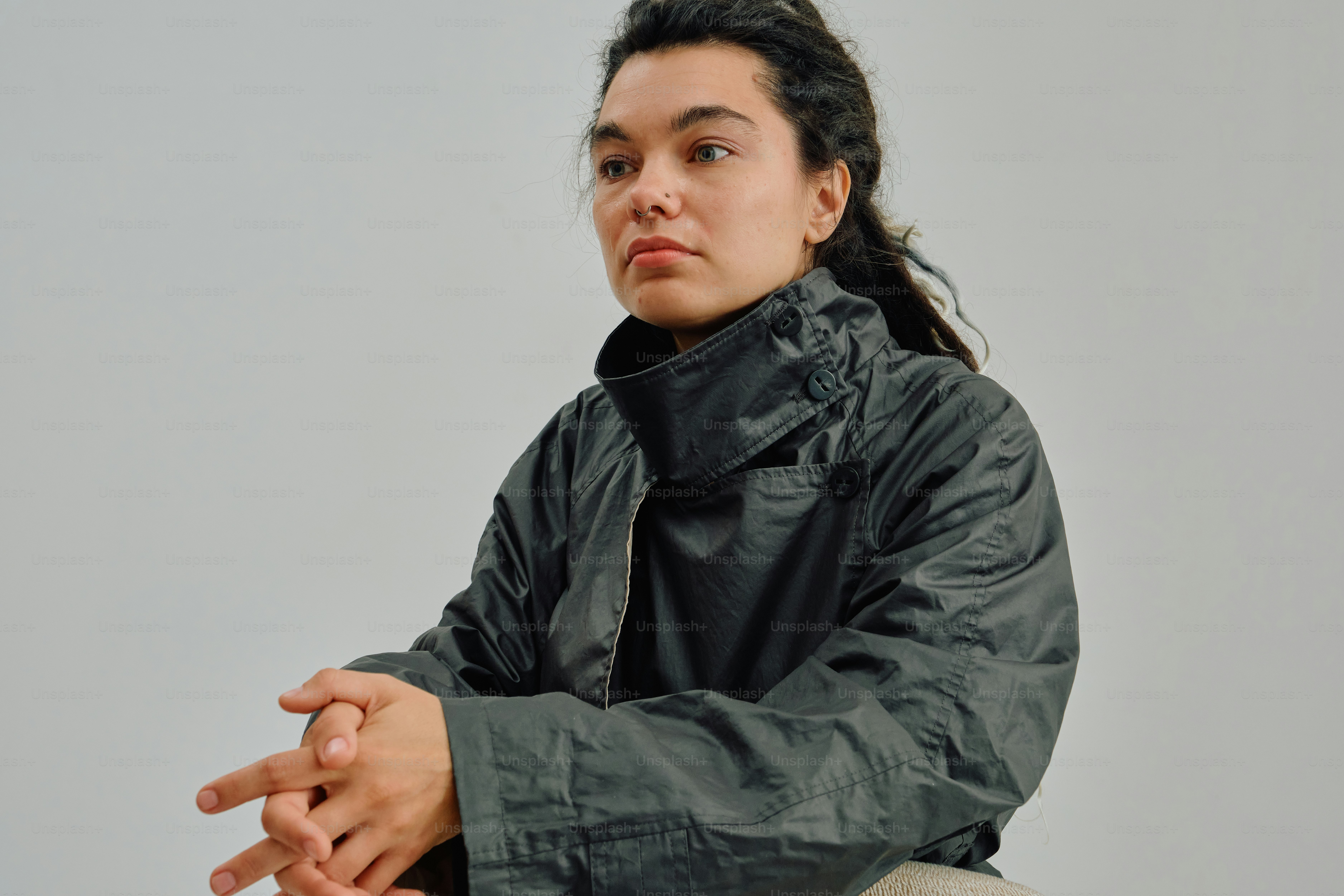 A person with dreadlocks and a nose ring wearing a dark grey jacket