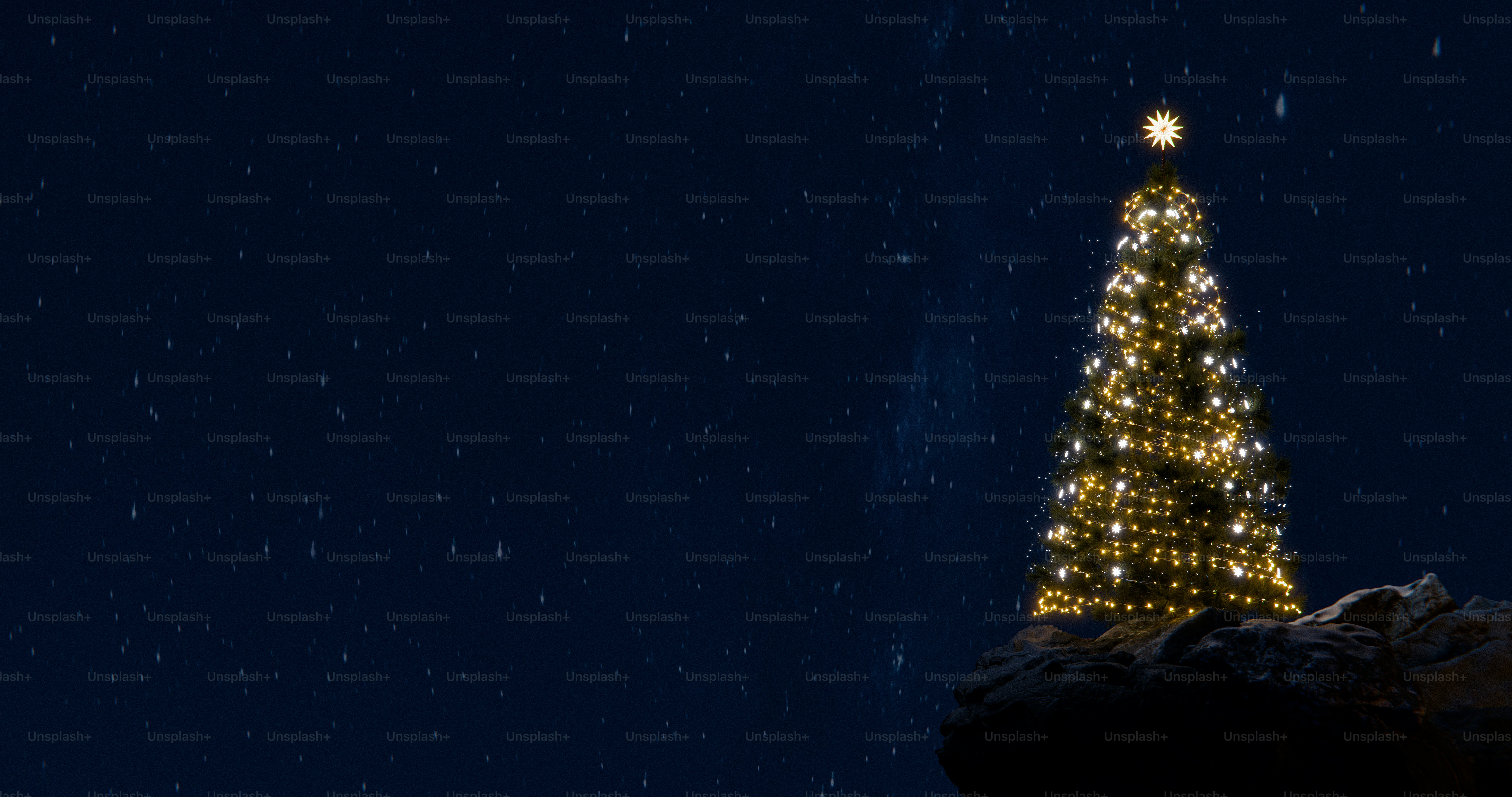 A lit Christmas tree with a star topper on a rocky cliff at night