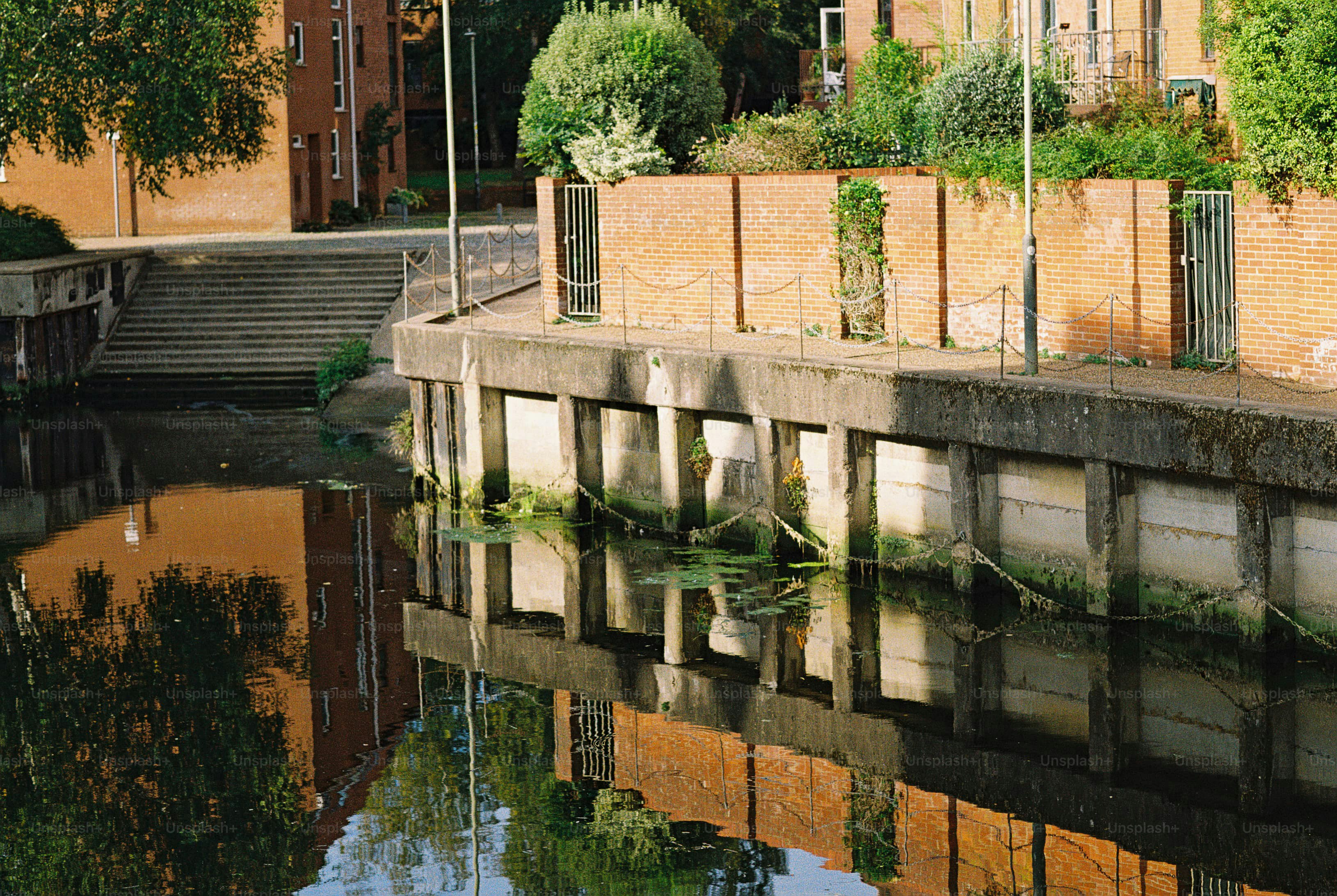 A brick wall and concrete embankment reflecting in a calm canal