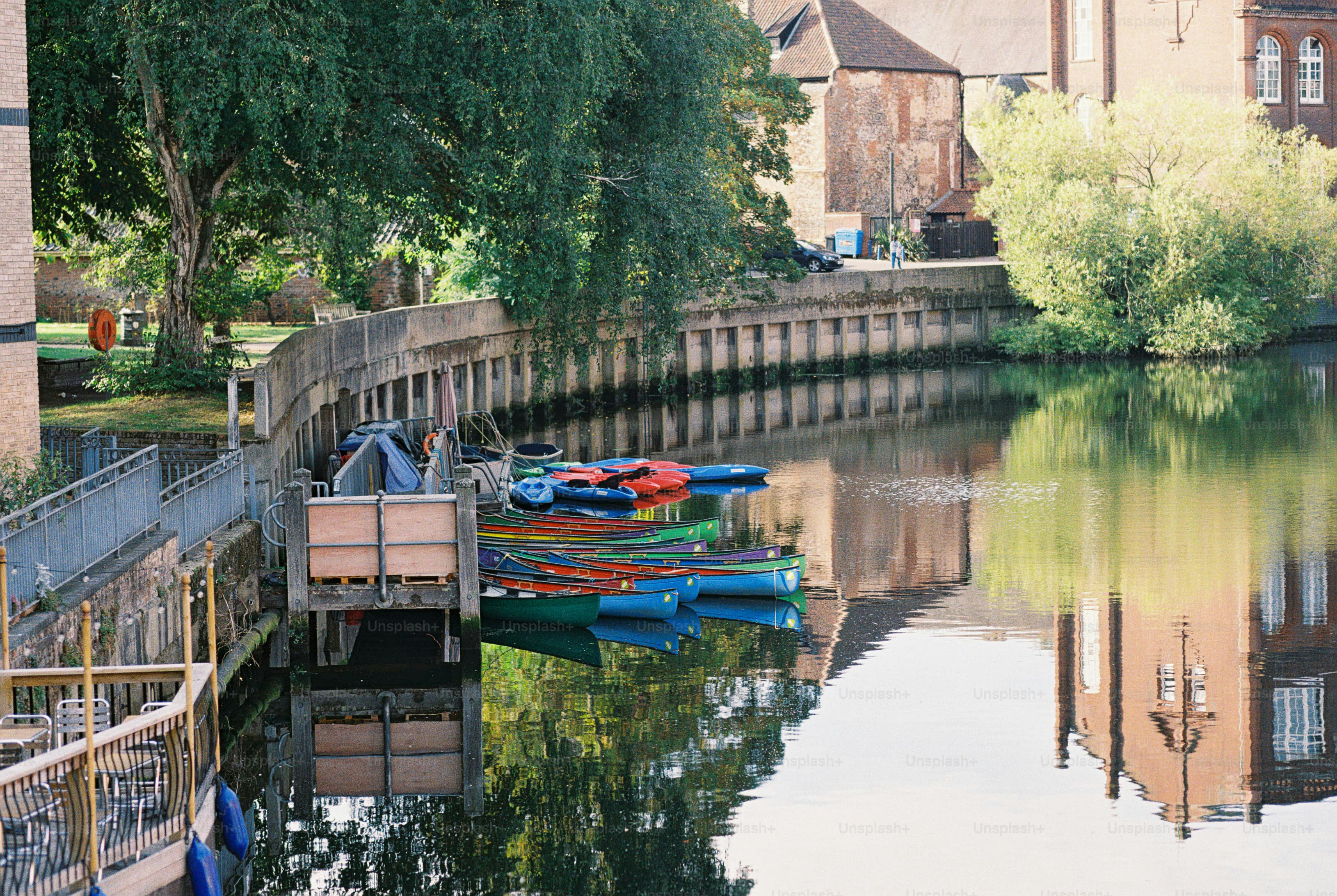 Colorful canoes moored at a wooden dock on a calm river near trees